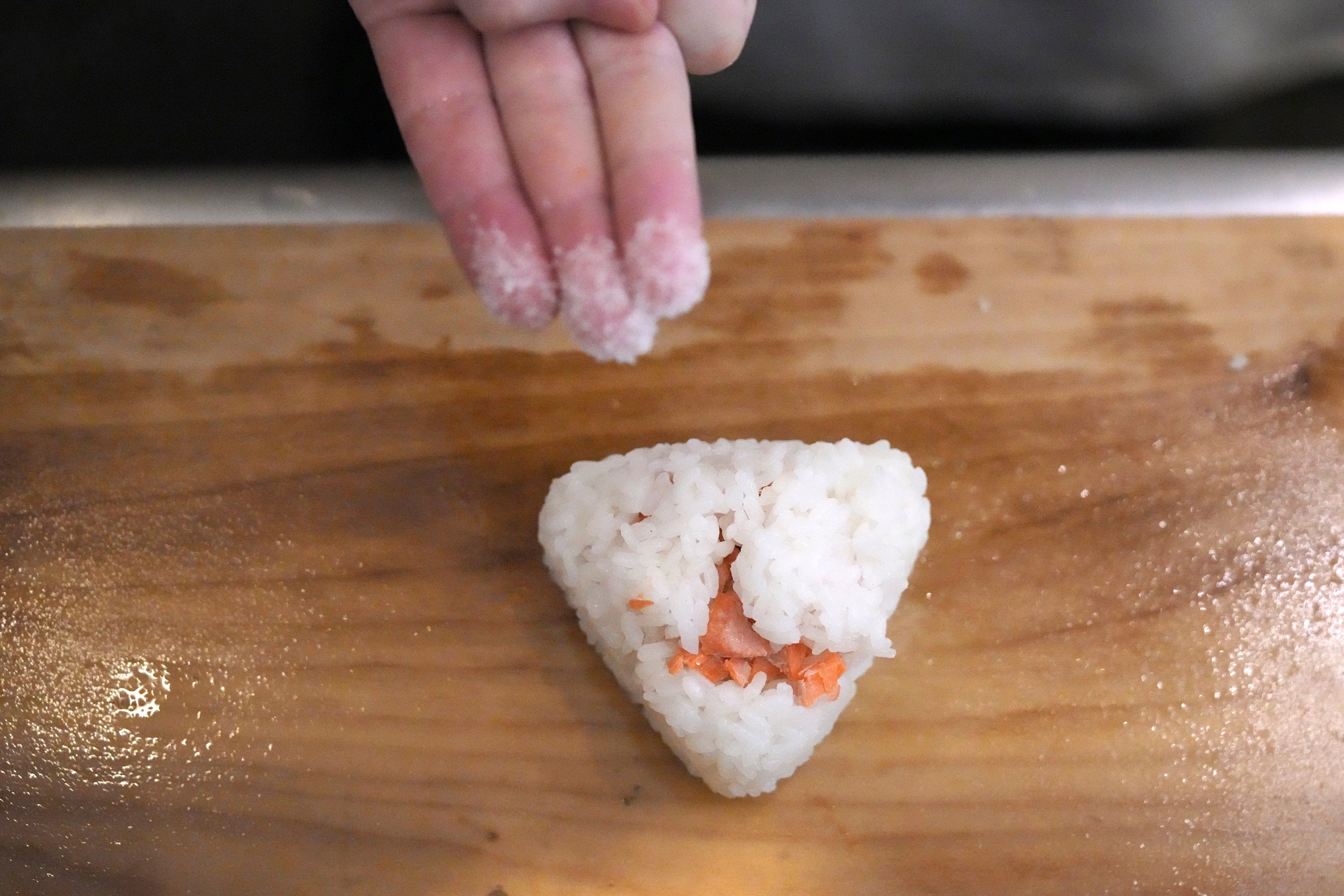 Yosuke Miura makes a rice ball with pieces of grilled salmon at Onigiri Asakusa Yadoroku