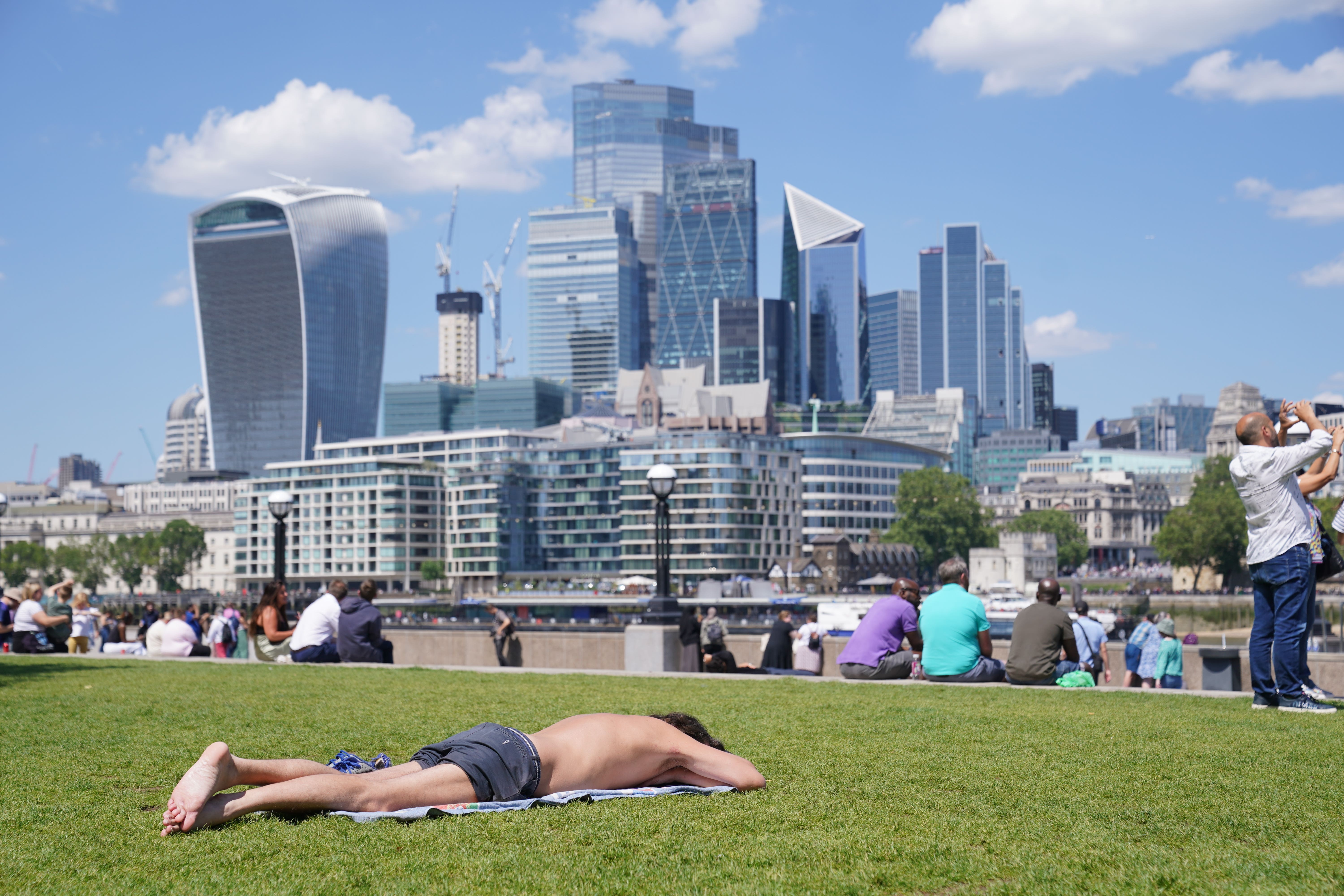 People enjoy the hot weather with a view of the City of London. London stocks climbed higher on Monday (Lucy North/PA)