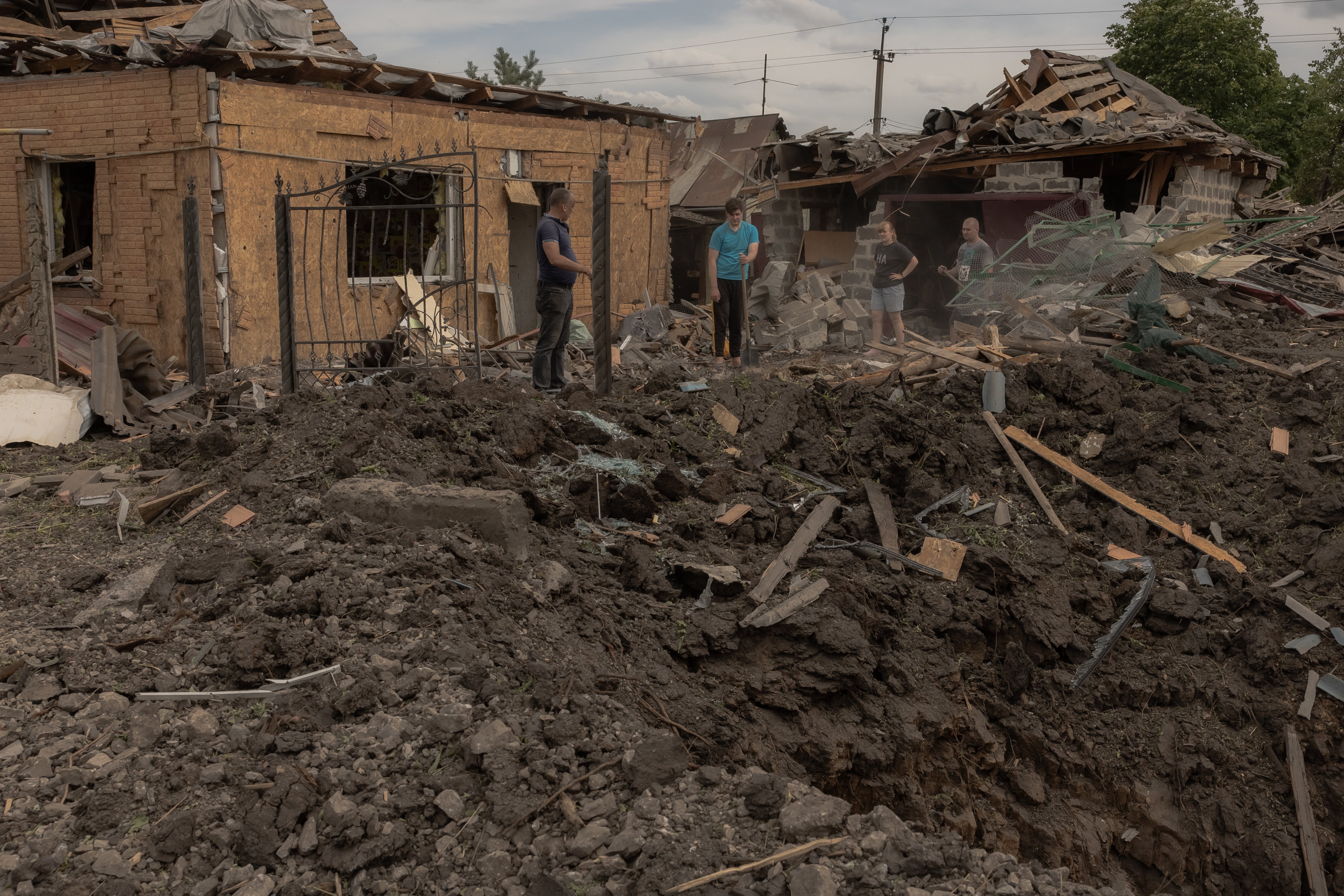 Residents clean debris next to heavily damaged houses following shelling in Pokrovsk, eastern Donetsk region