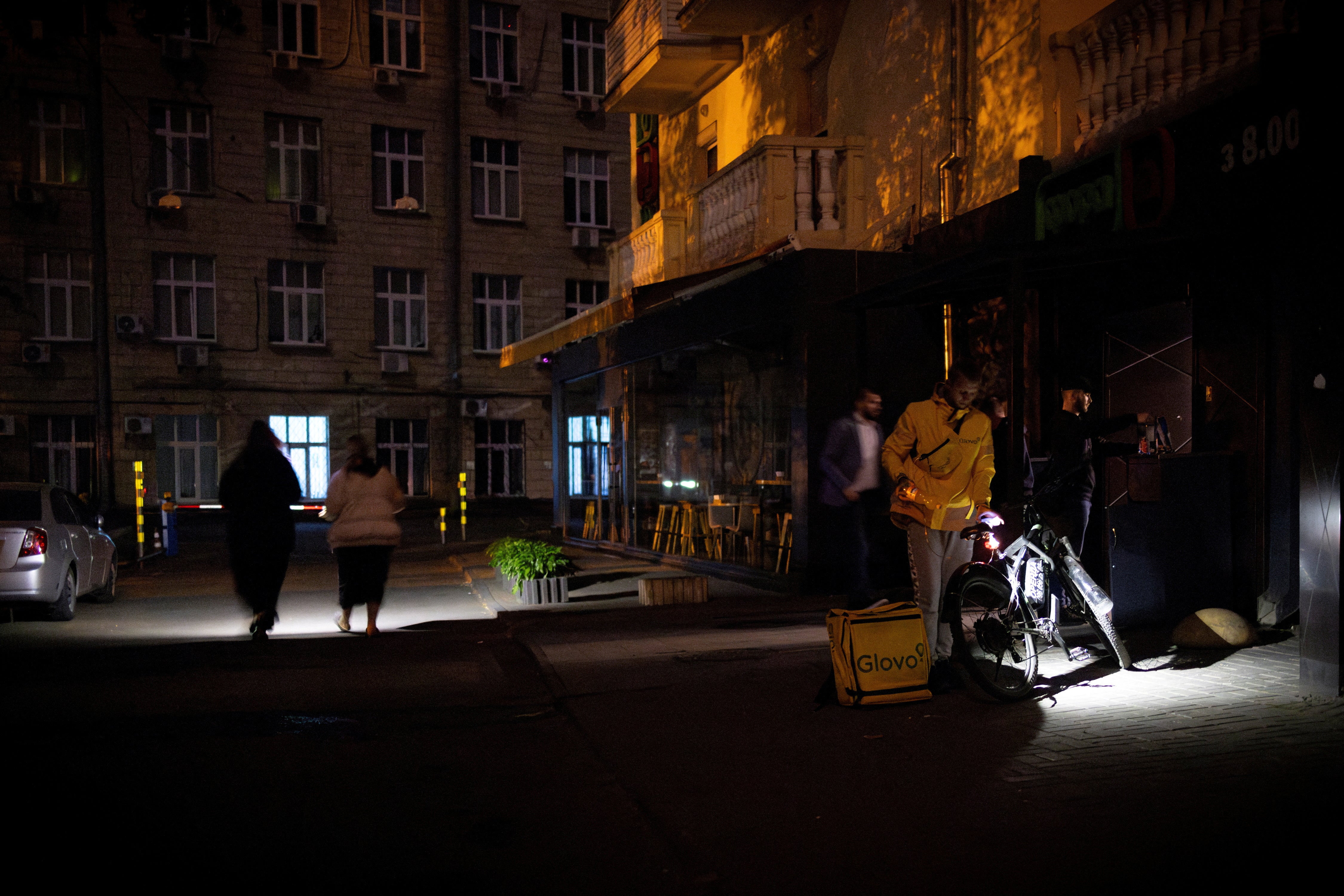 People use torches as they leave a supermarket during a partial electricity blackout in the Ukrainian capital Kyiv in May