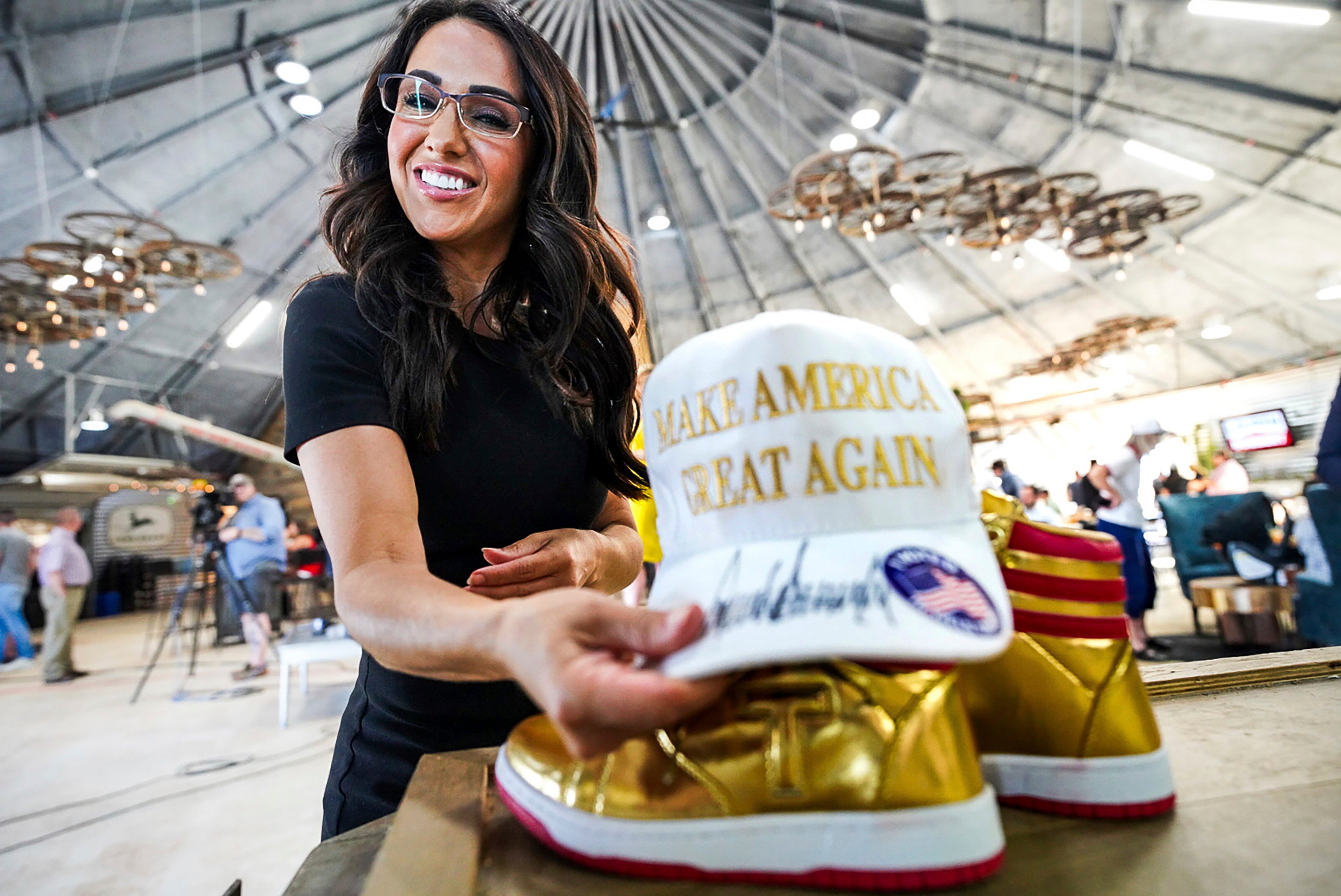 Boebert arranges a Make America Great Again hat and a pair of gold Converse All-Stars basketball shoes on the stage at her primary election watch party in June in Windsor