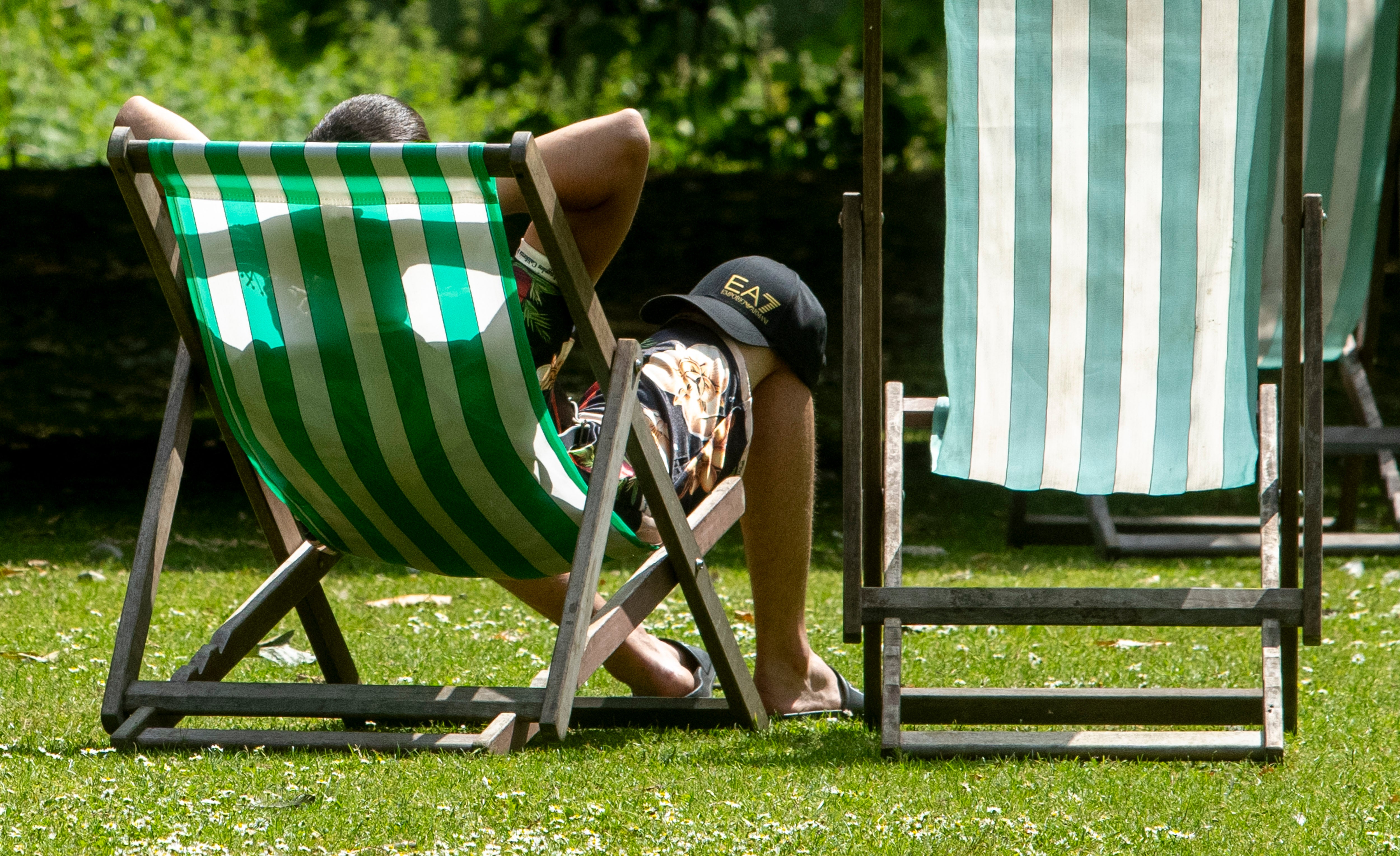 Members of the public enjoy the summer sun in Green Park in London.