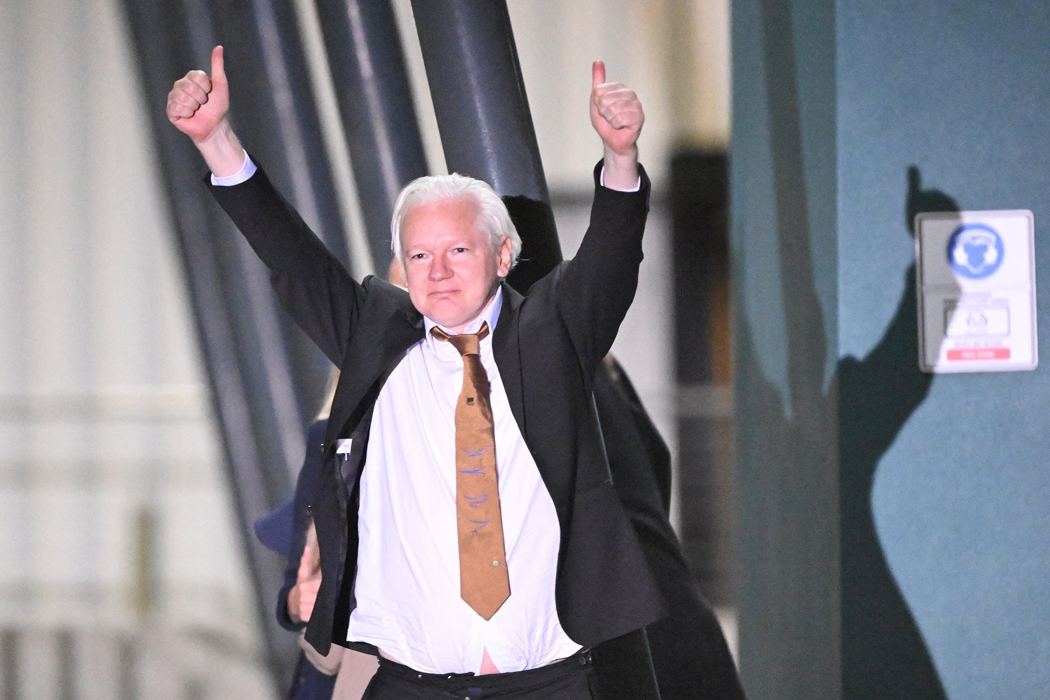 Julian Assange gives the thumbs up after arriving in Canberra