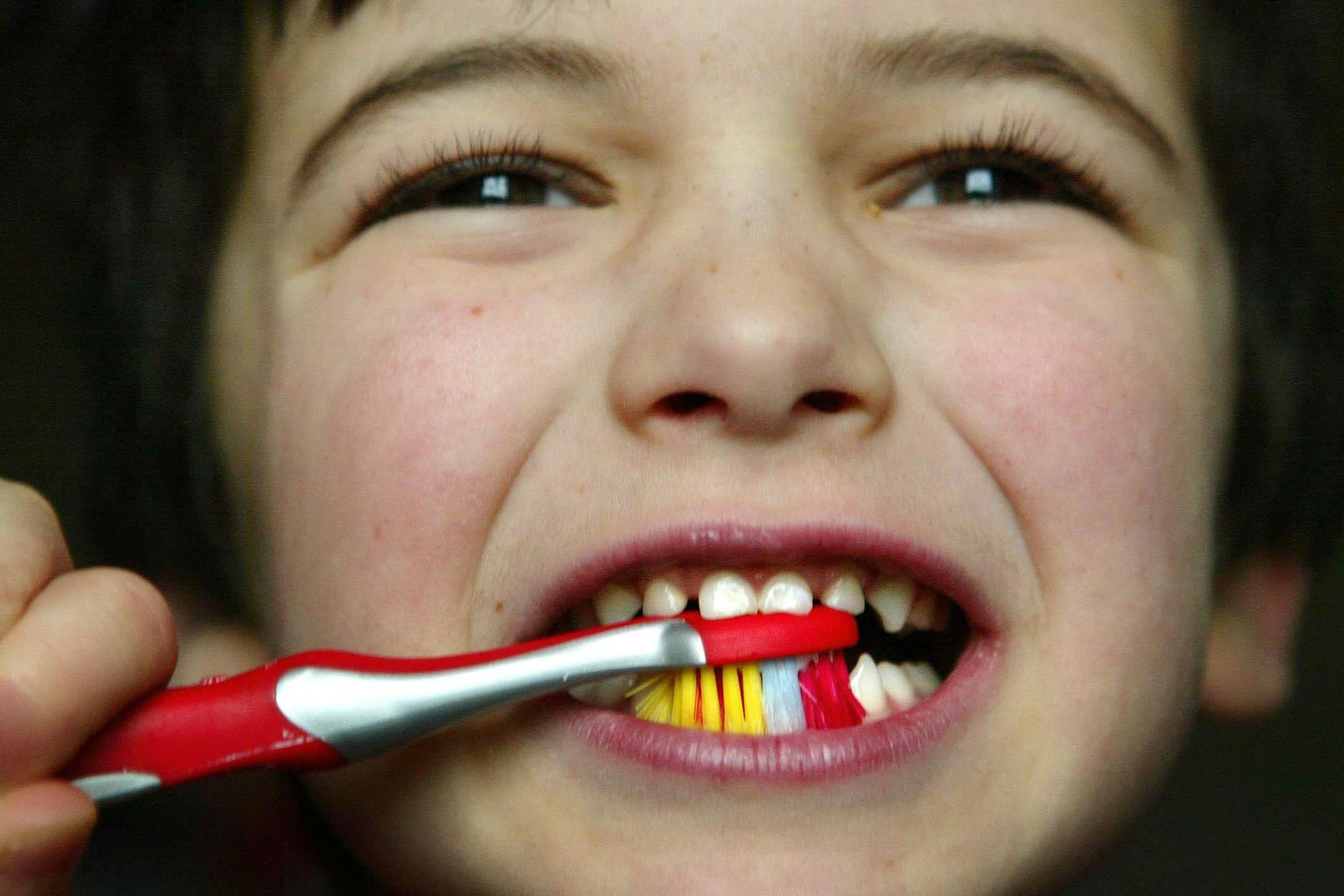 A young child brushing his teeth (PA)