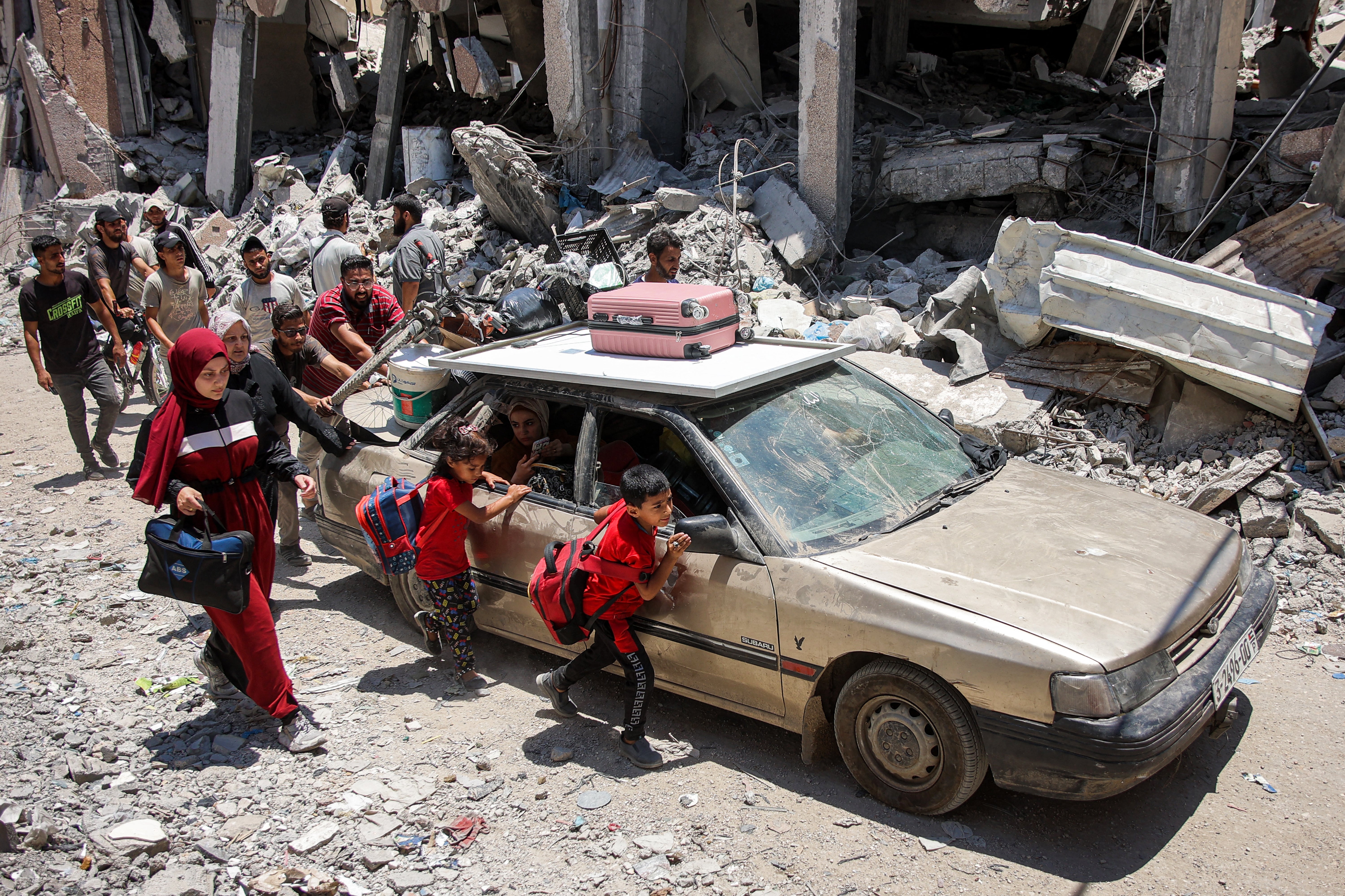 Children walk alongside a vehicle while evacuating with others from the Tuffah neighbourhood in the east of Gaza City heading towards areas in the west