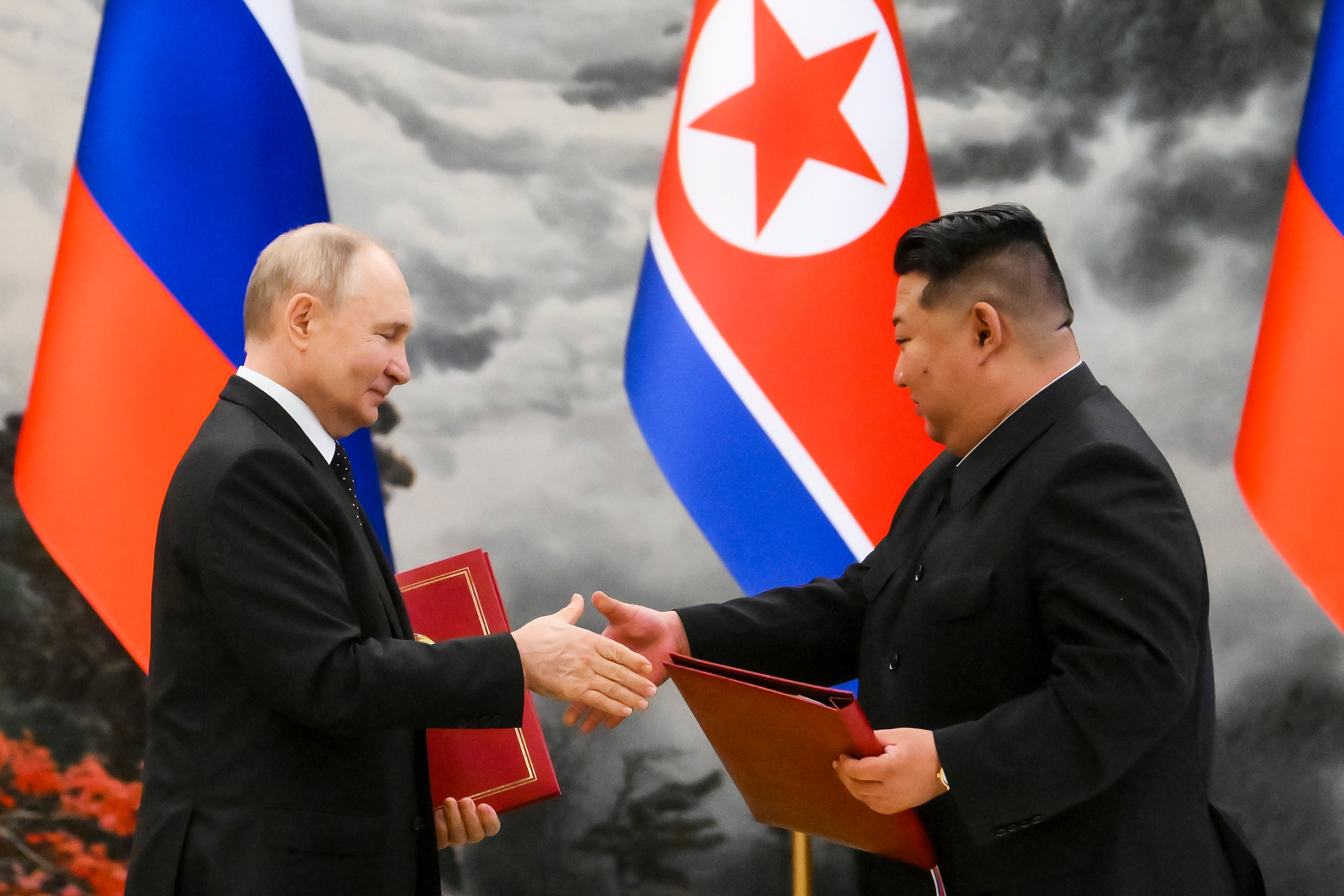 Russian President Vladimir Putin (left) and North Korean leader Kim Jong-un exchange documents during a ceremony for their new partnership in Pyongyang, North Korea, in June