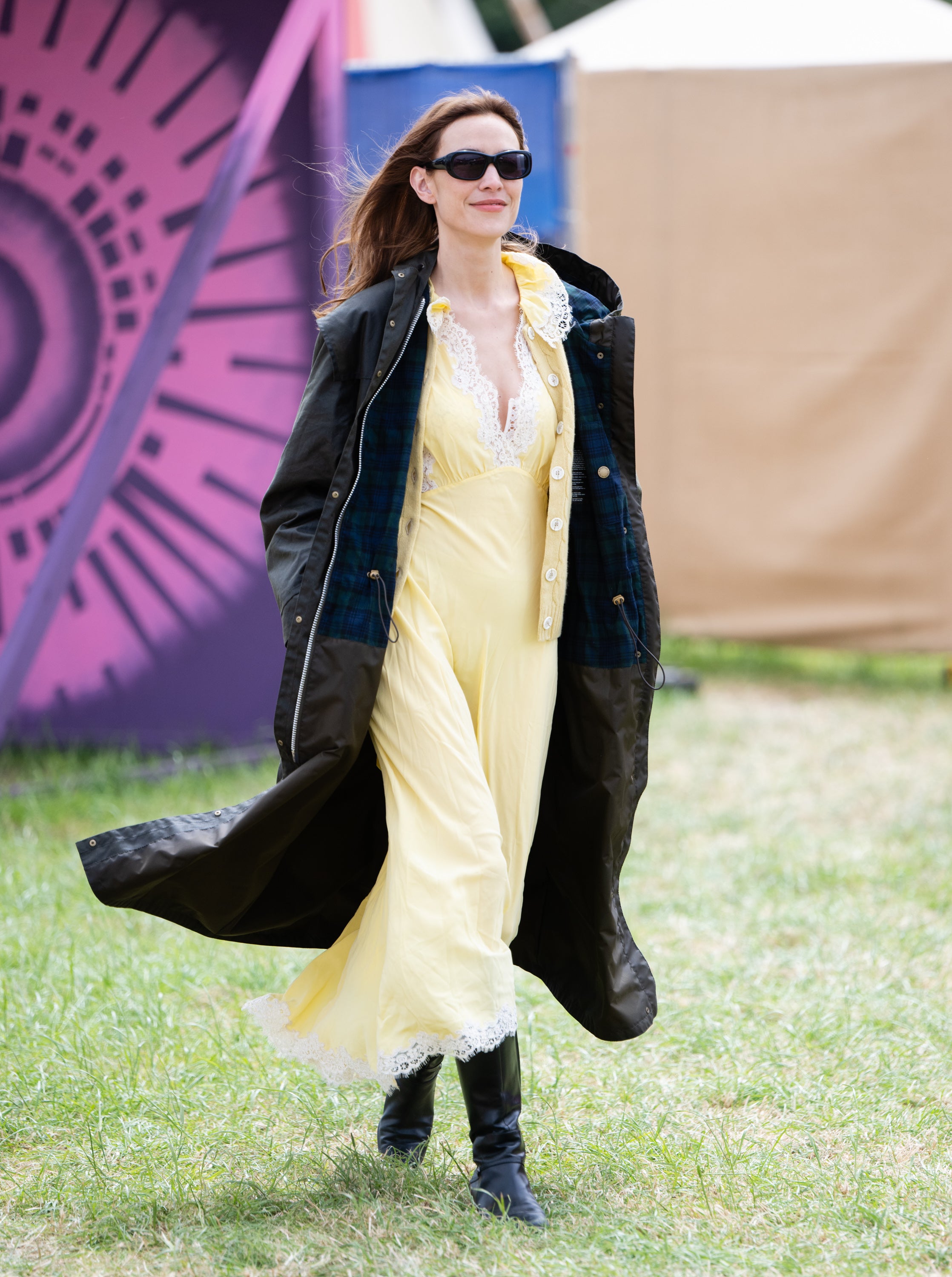 Alexa Chung opted for a silk lemon-yellow dress with white yellow embellishments, worn underneath an oversized, full-length Barbour jacket with black boots