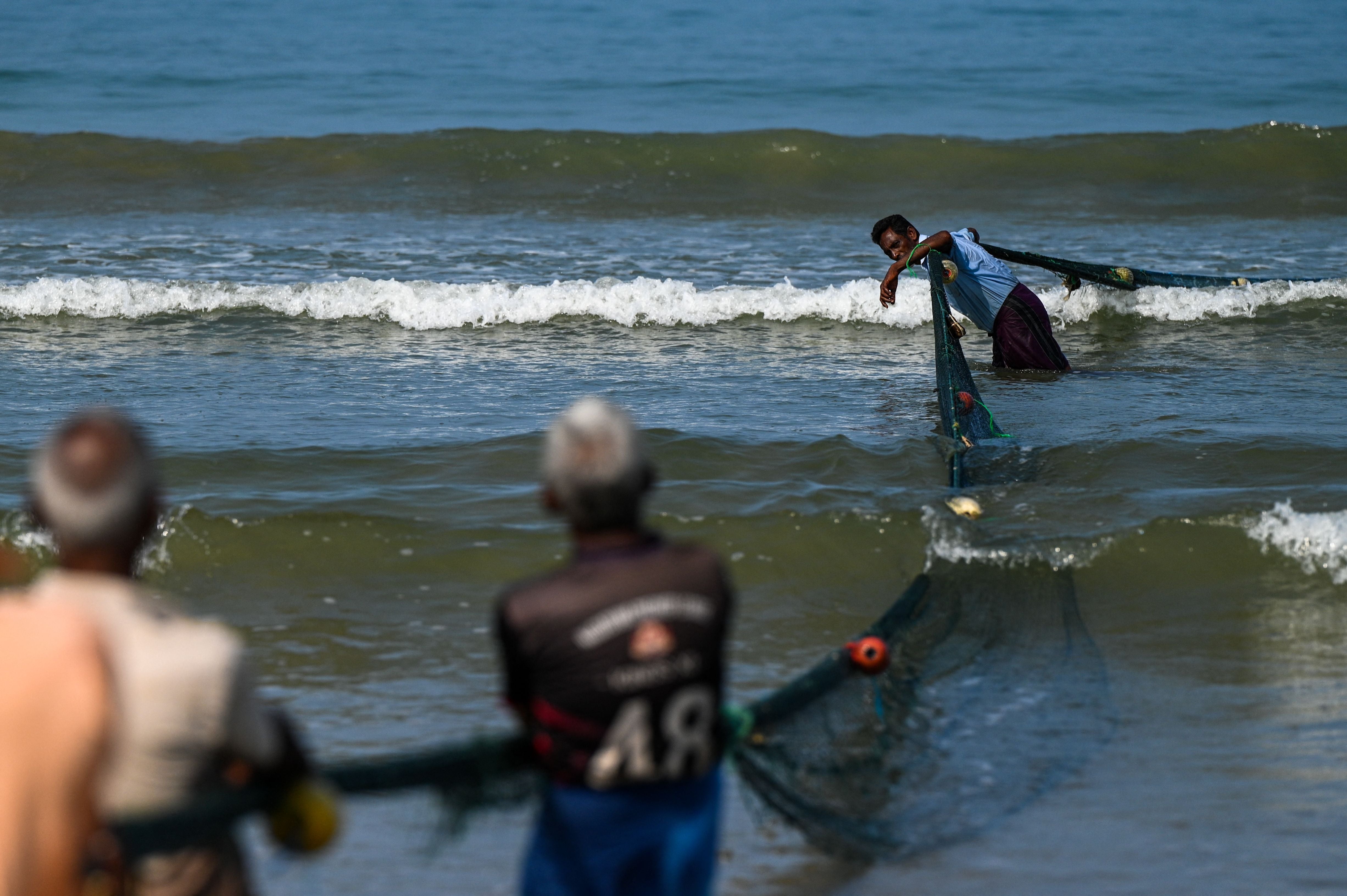 Fishermen pull a fishing net at a beach in Galle, Sri Lanka