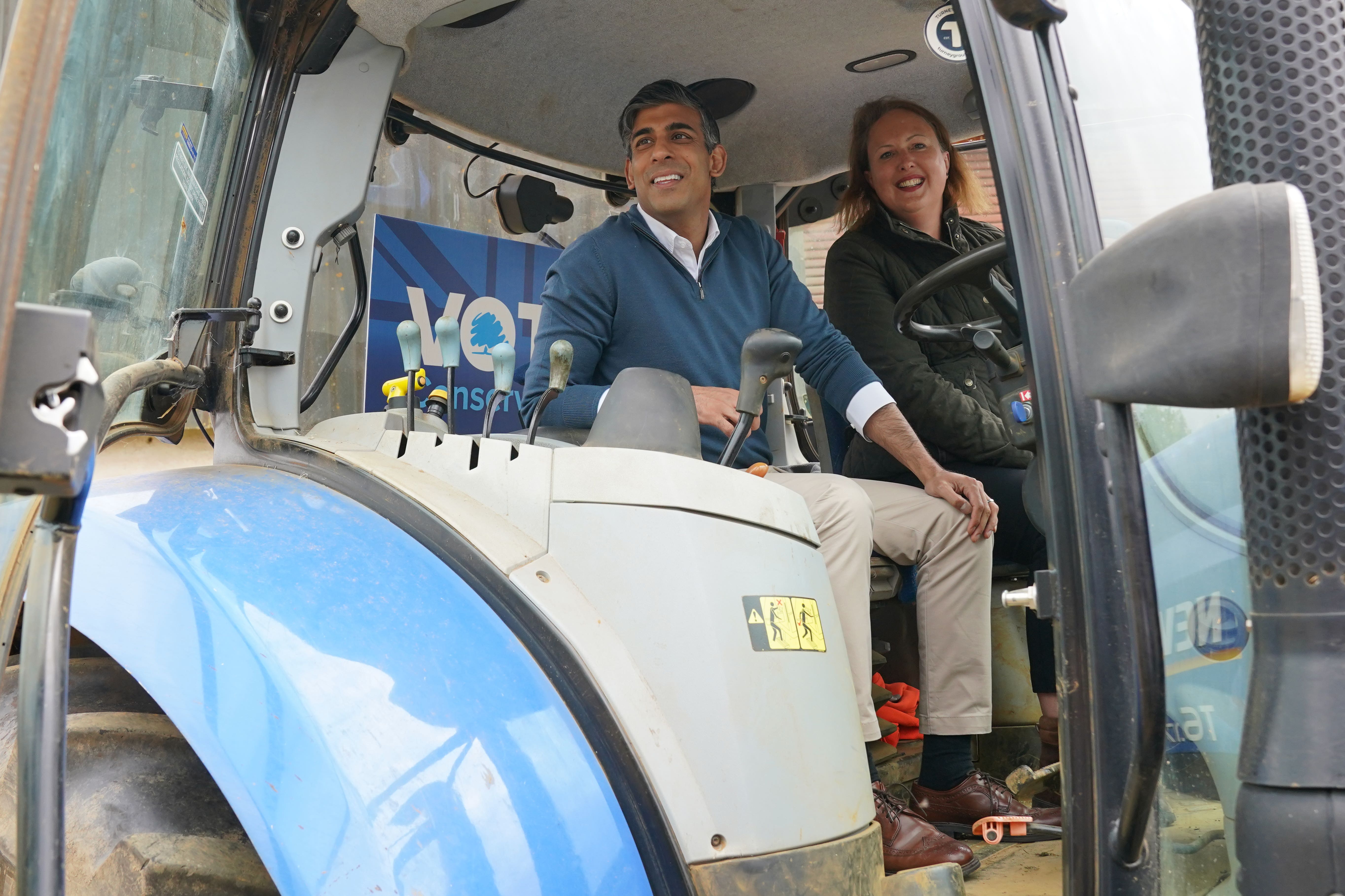 Prime Minister Rishi Sunak and Attorney General and parliamentary candidate for Banbury Victoria Prentis sit in a tractor during a visit to Wykham Park Farm (Jonathan Brady/PA)