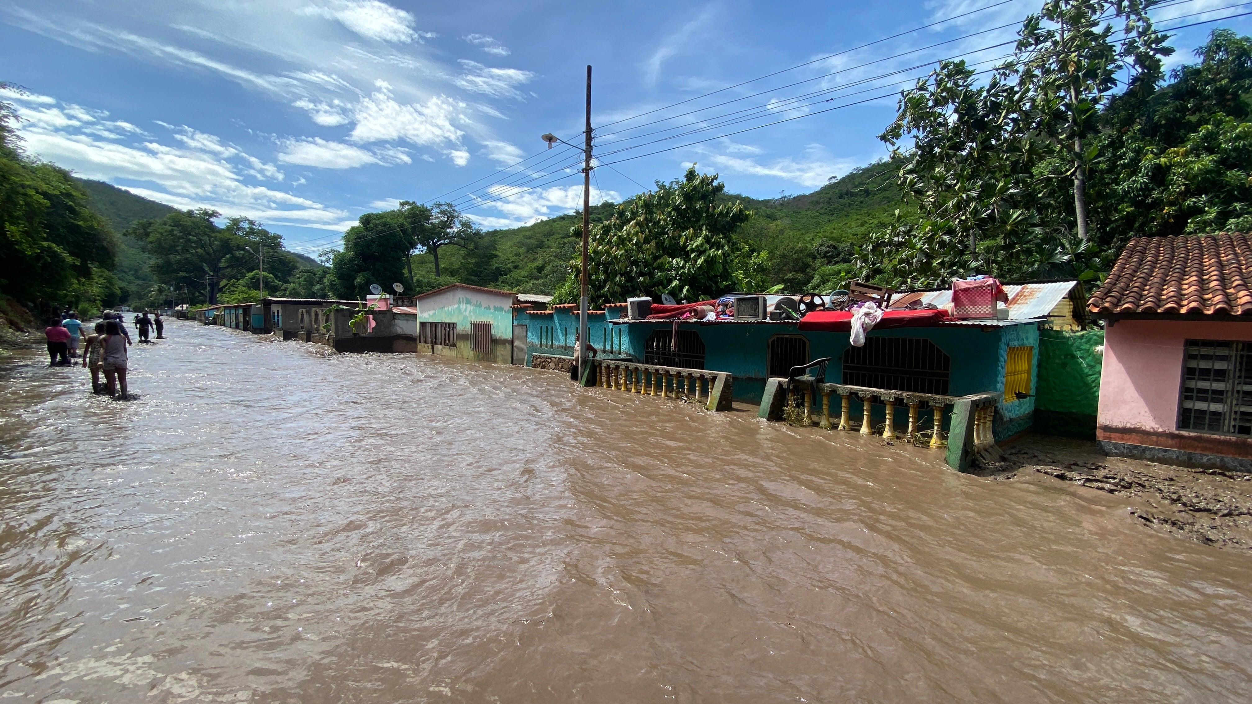 People stand outside their flooded homes following the passage of hurricane Beryl in Sucre State of Venezuela