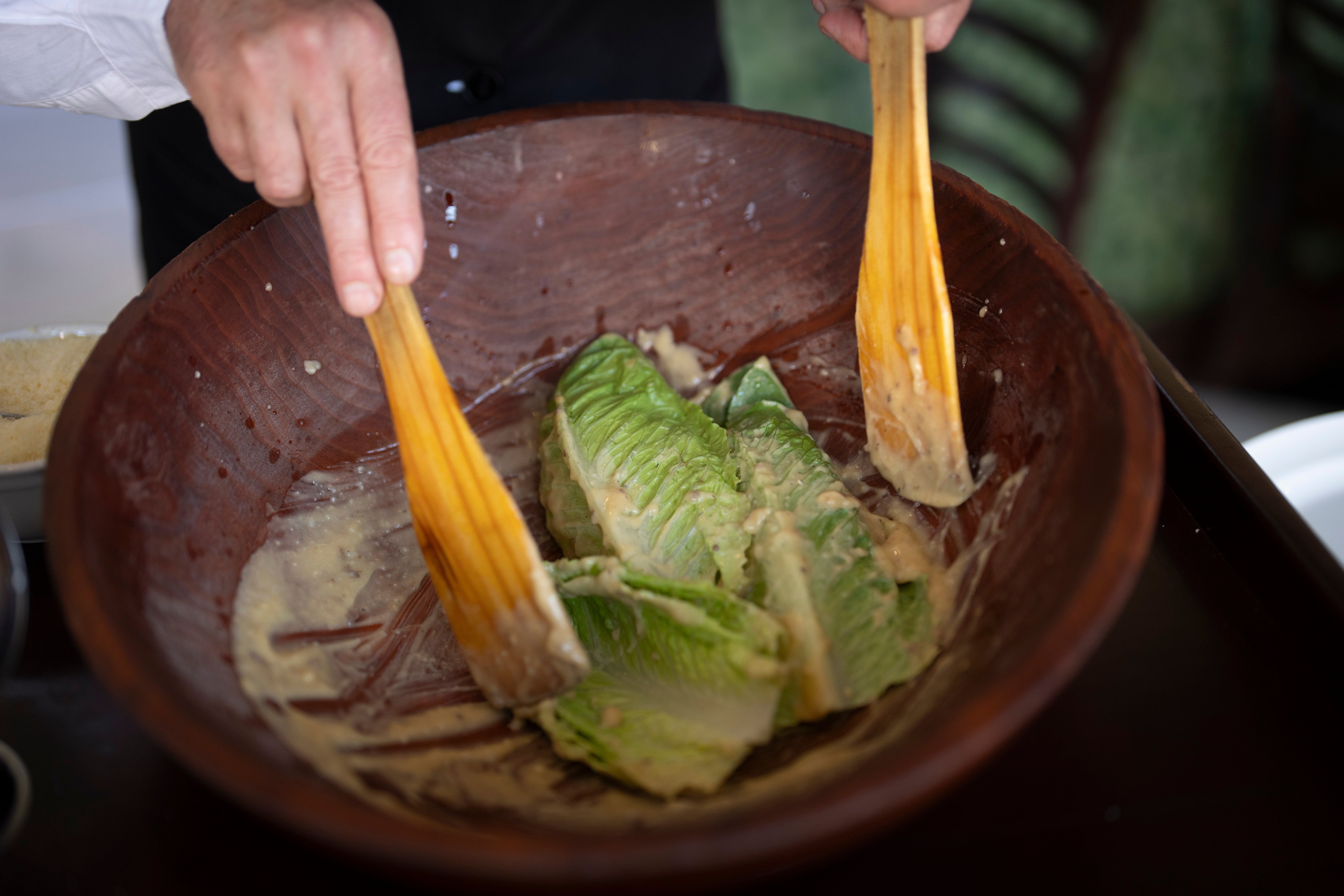 Salad Master Efrain Montoya mixes Romaine leaves with other ingredients as he prepares a Caesar salad at Ceasar’s restaunt