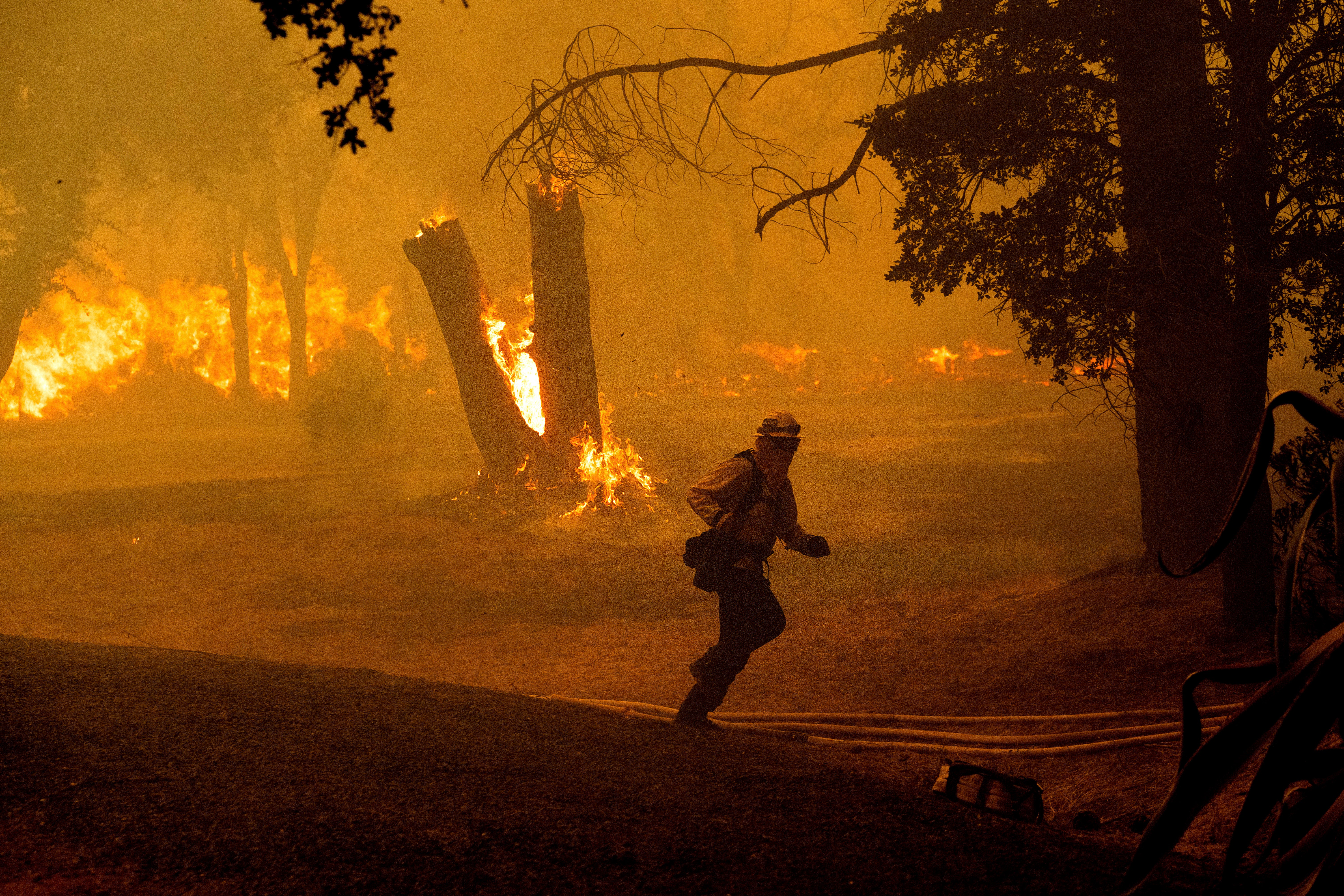 A firefighter runs while battling the Thompson Fire burning in Oroville, California