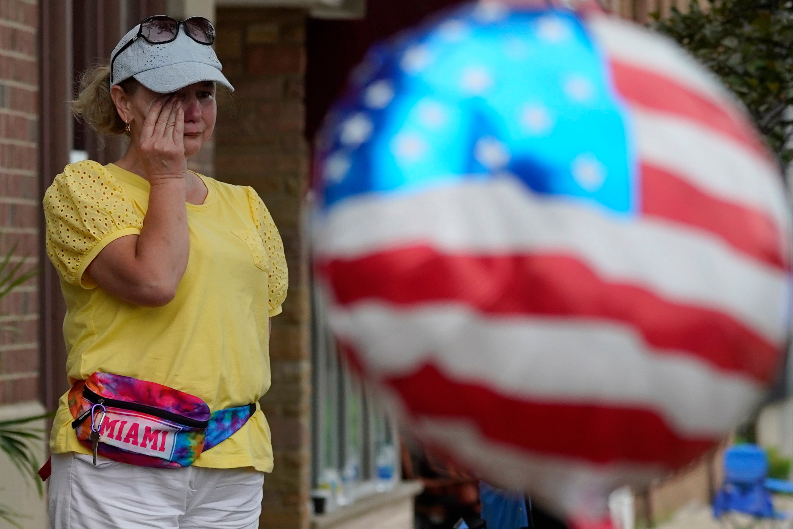 A woman wipes away tears after a mass shooting at an Independence Day parade that left seven people dead