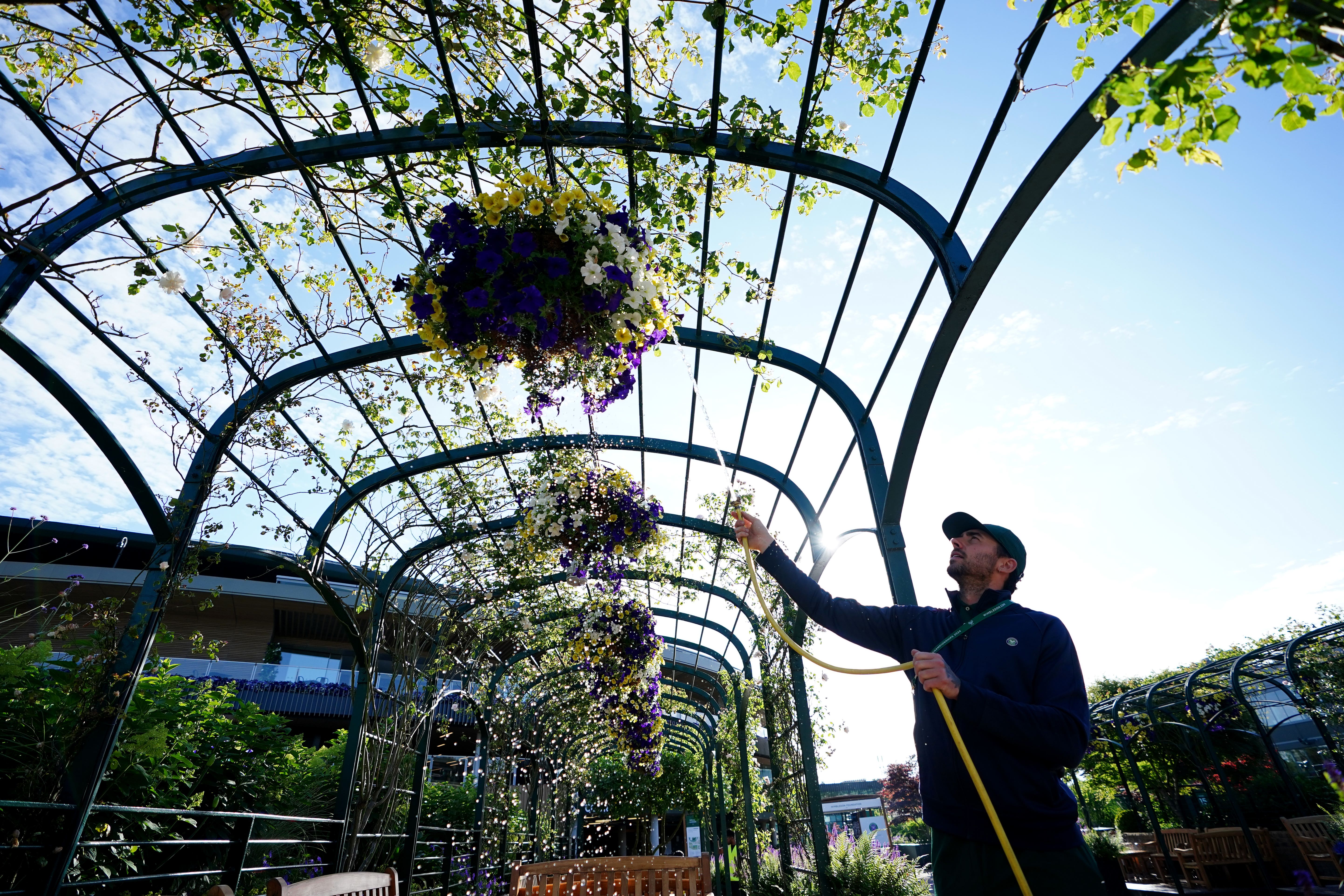 A member of the ground staff waters the flowers at Wimbledon (Zac Goodwin/PA)