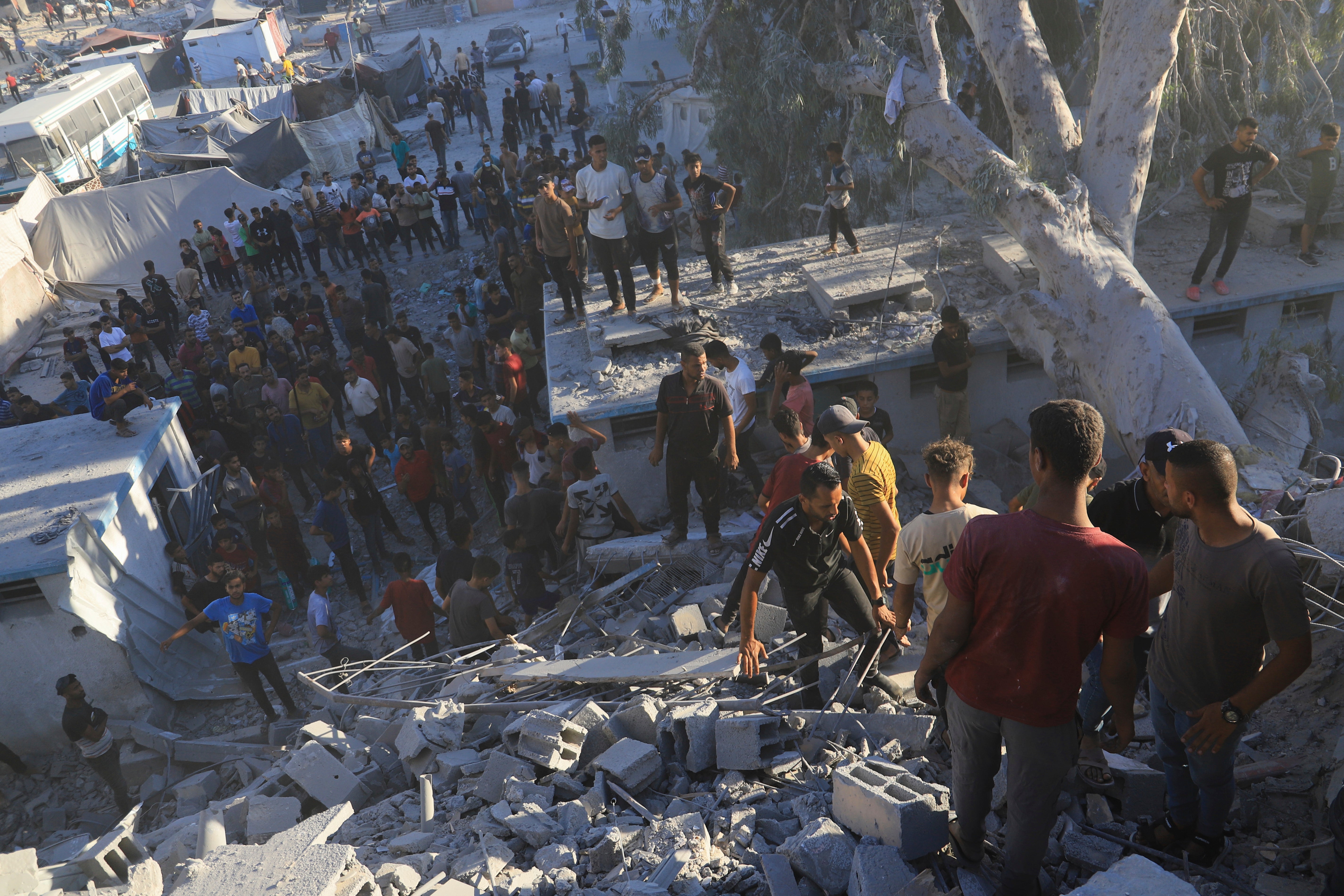 Palestinians search for bodies and survivors in the rubble of a residential building destroyed in an Israeli airstrike