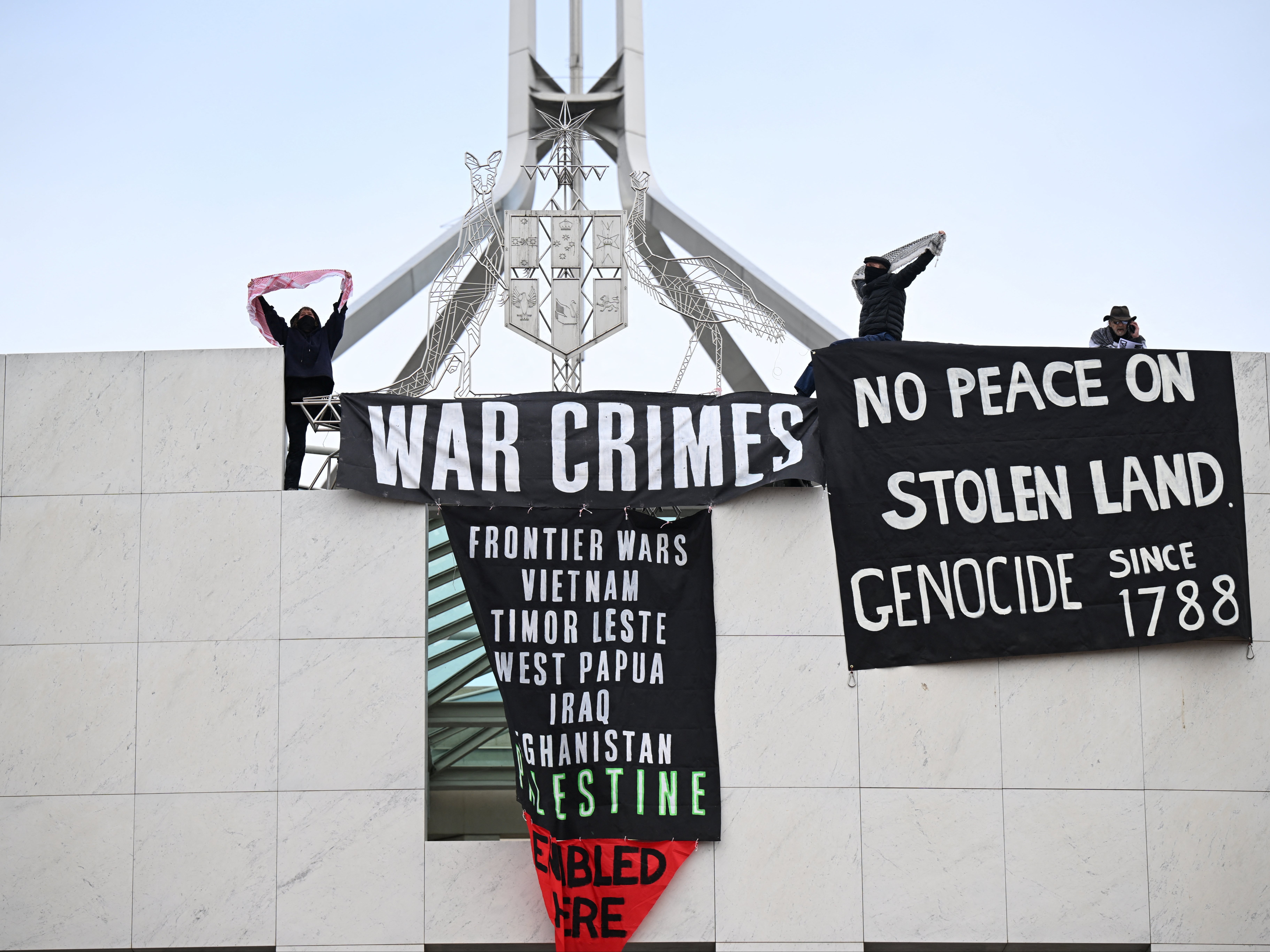 Pro-Palestinian protesters hang banners from the top of the Australian parliament in Canberra on 4 July 2024
