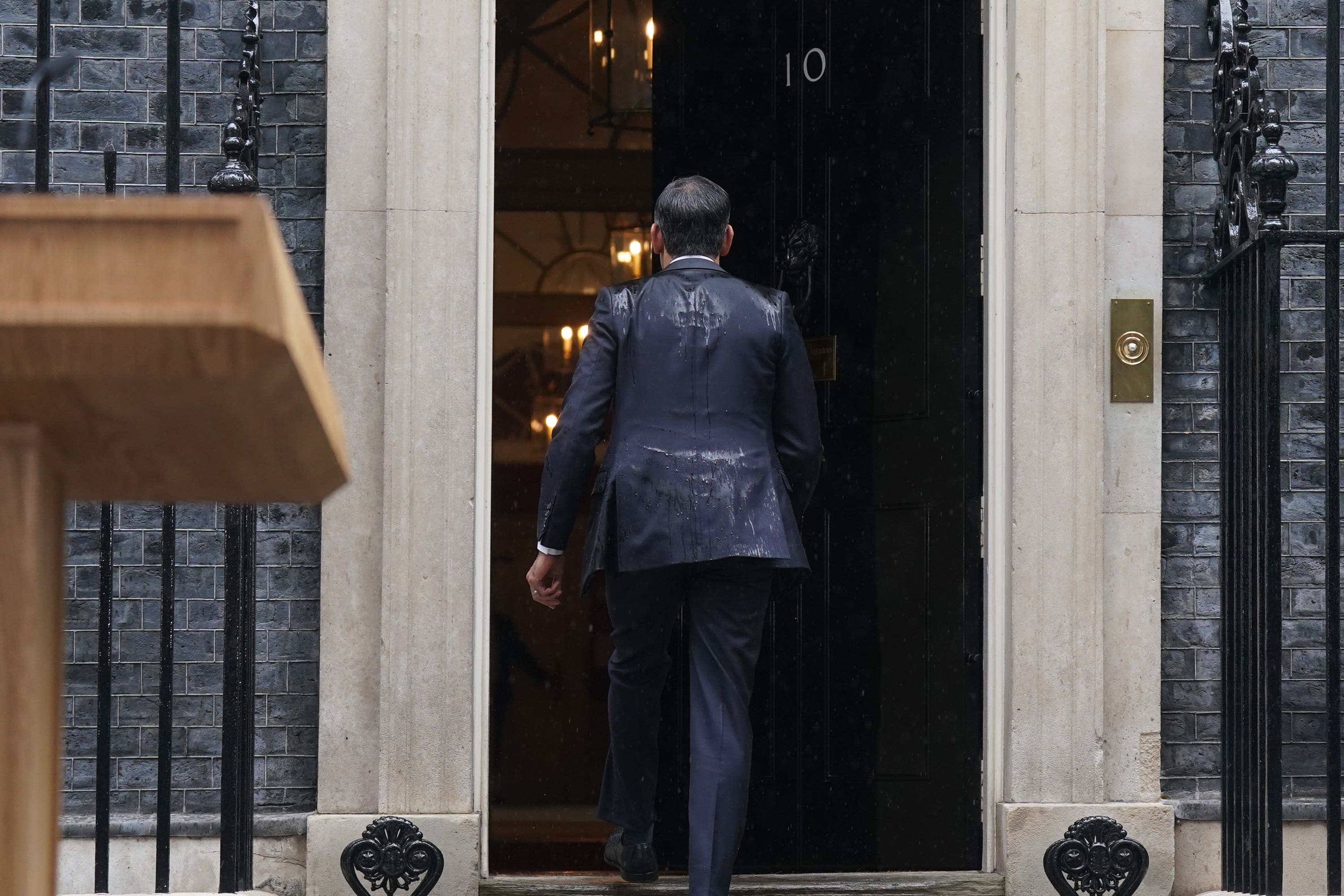 A rain-drenched Rishi Sunak re-enters No 10 after announcing the election (Stefan Rousseau/PA)