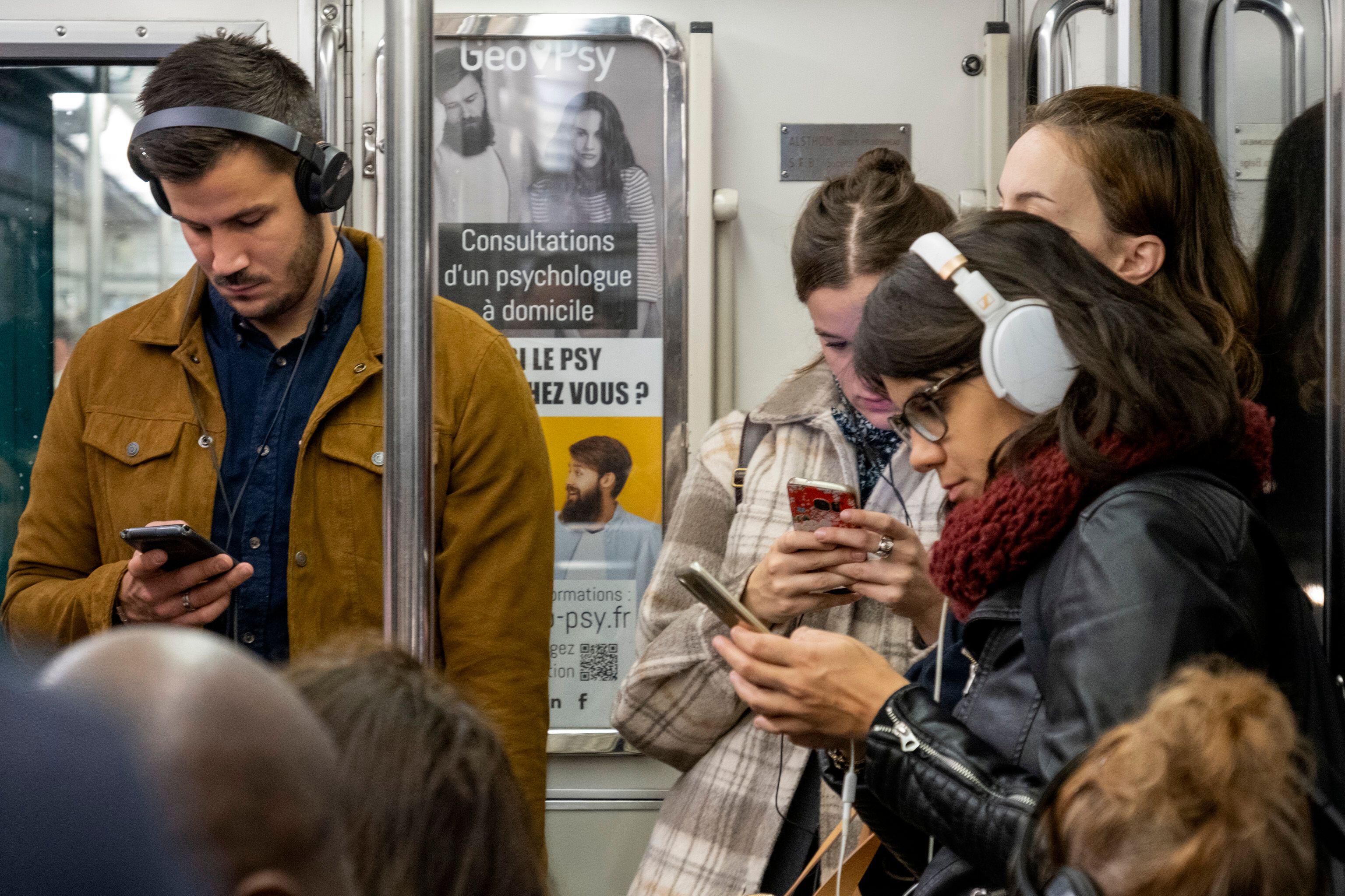 Young people standing and using smartphones in the parisian metro, Paris, France,