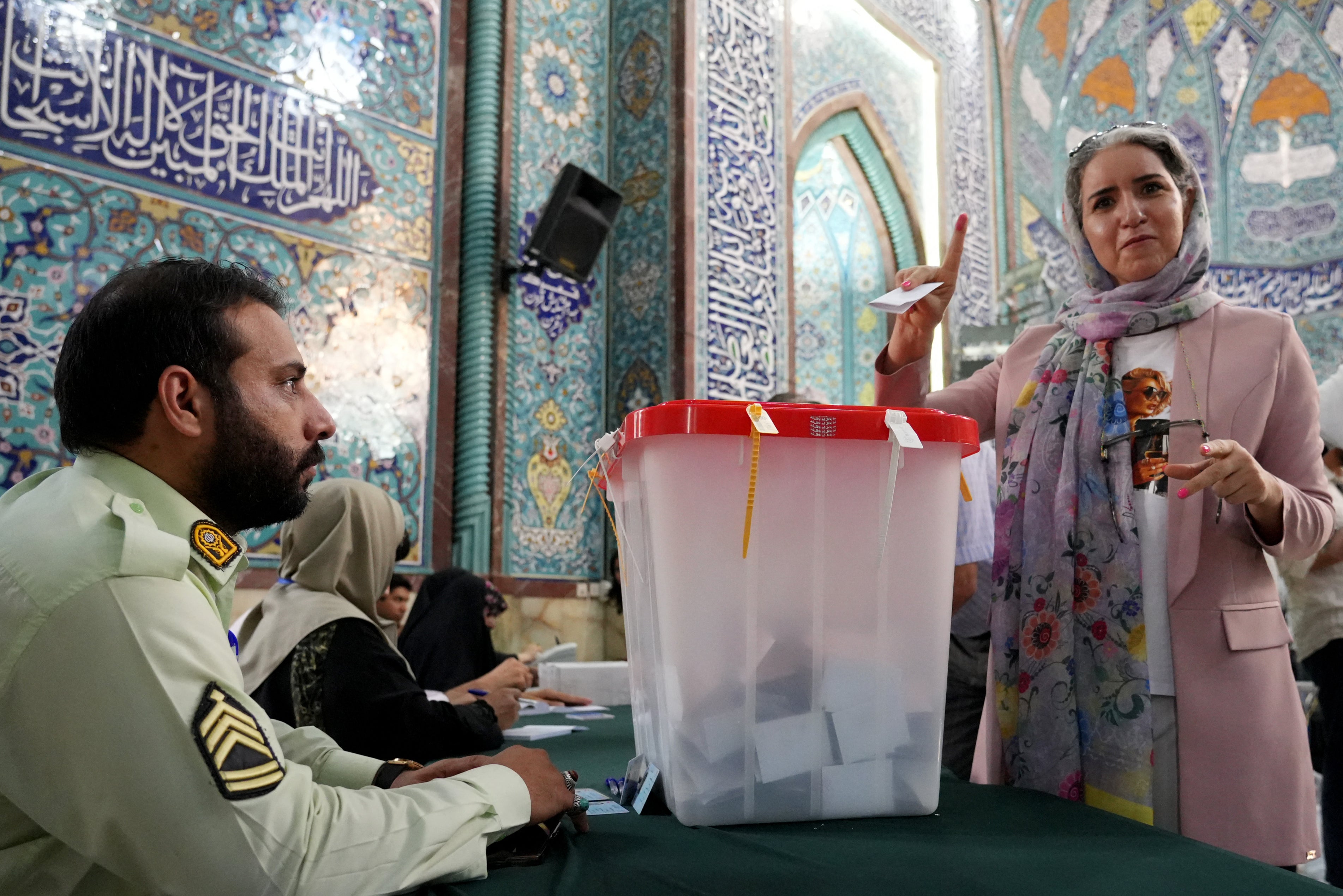 An Iranian woman shows her ink-stained finger after casting her ballot at a polling station, in Tehran