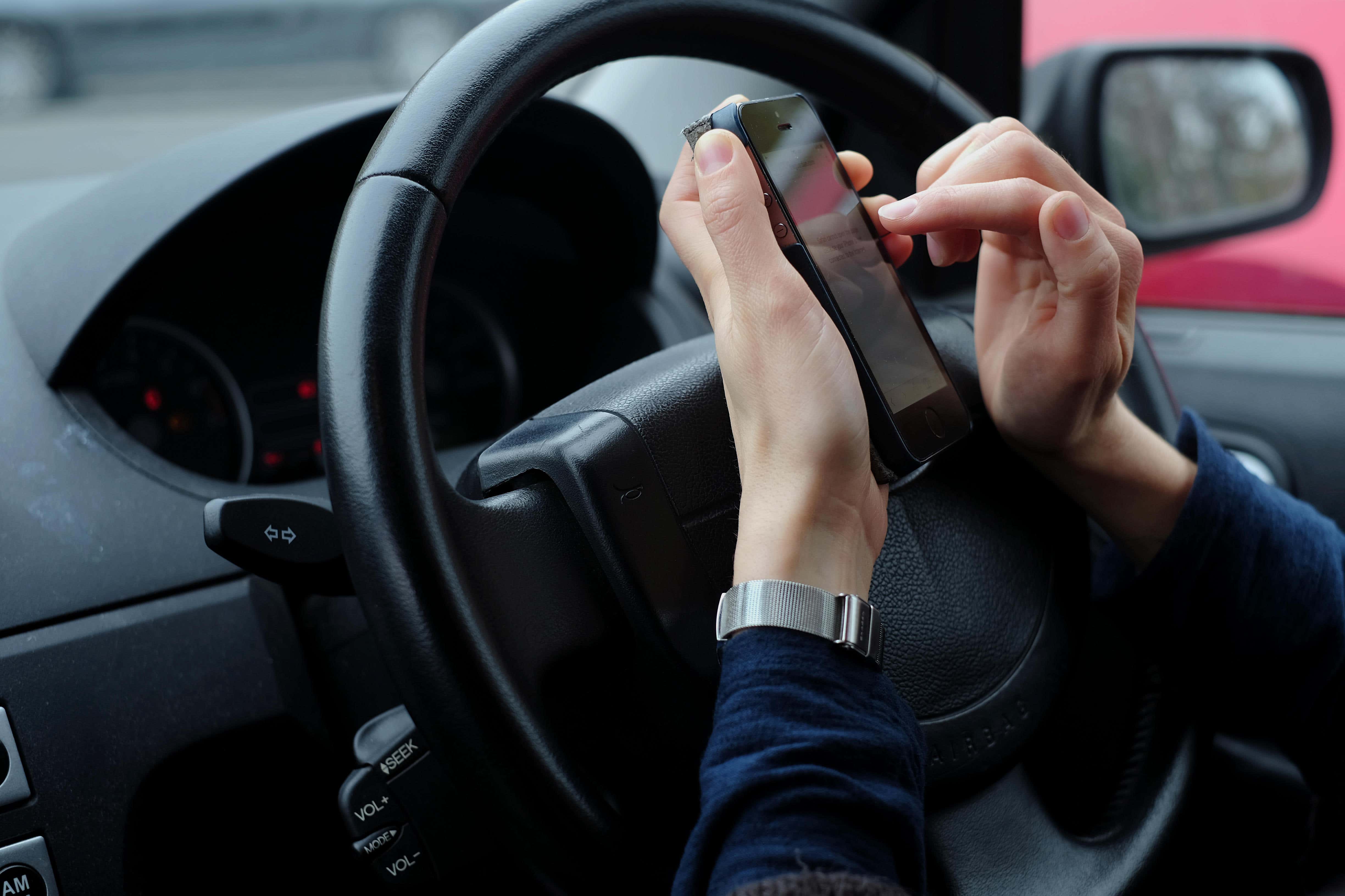 It is illegal for a hand-held device to be used for most actions while a vehicle is stopped at traffic lights or queuing in traffic (Alamy/PA)