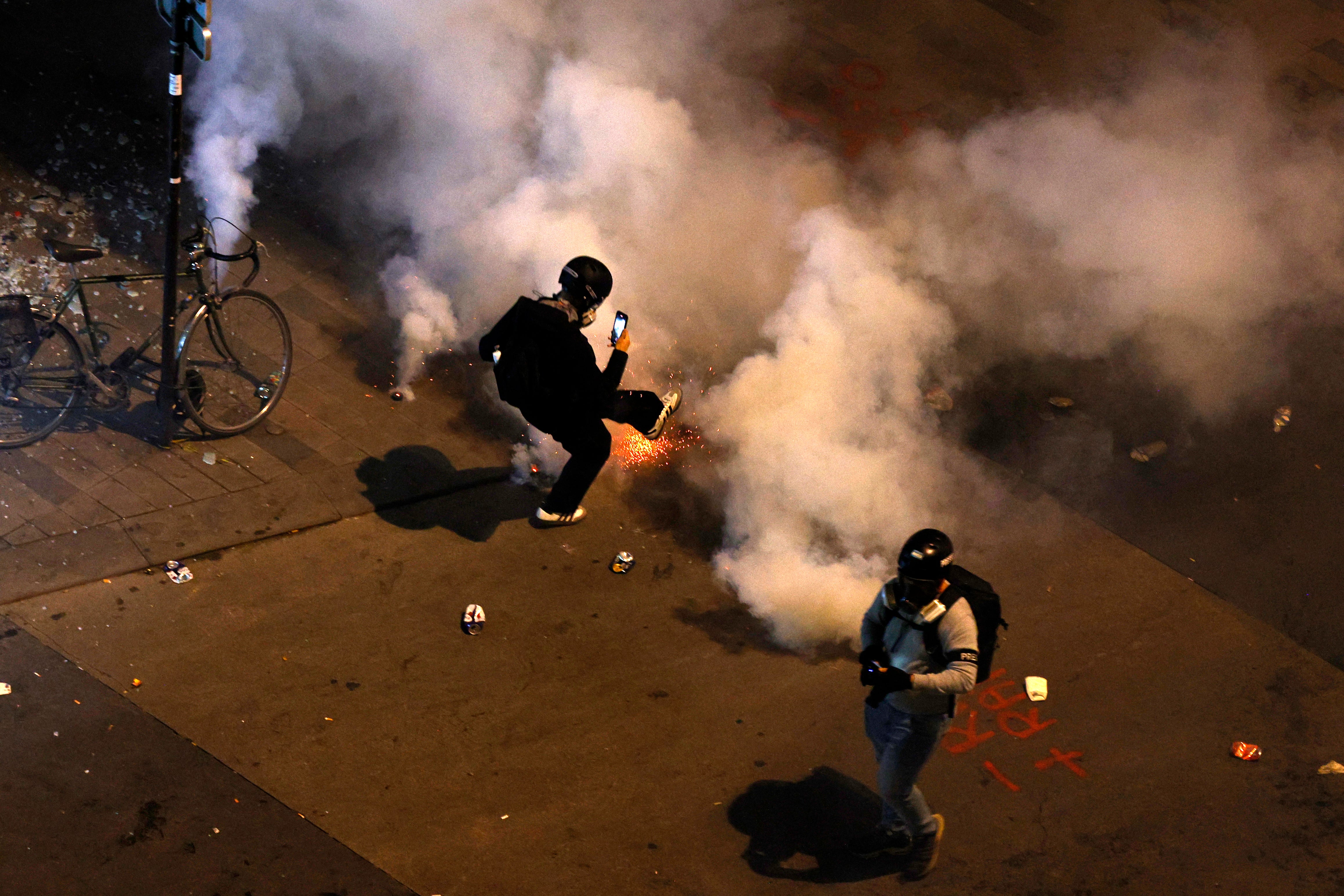 A protester kicks back a tear gas canister as clashes occur on the sidelines of an election night following the second round results of France’s legislative election at Republique Square in Paris on the night of 8 July 2024