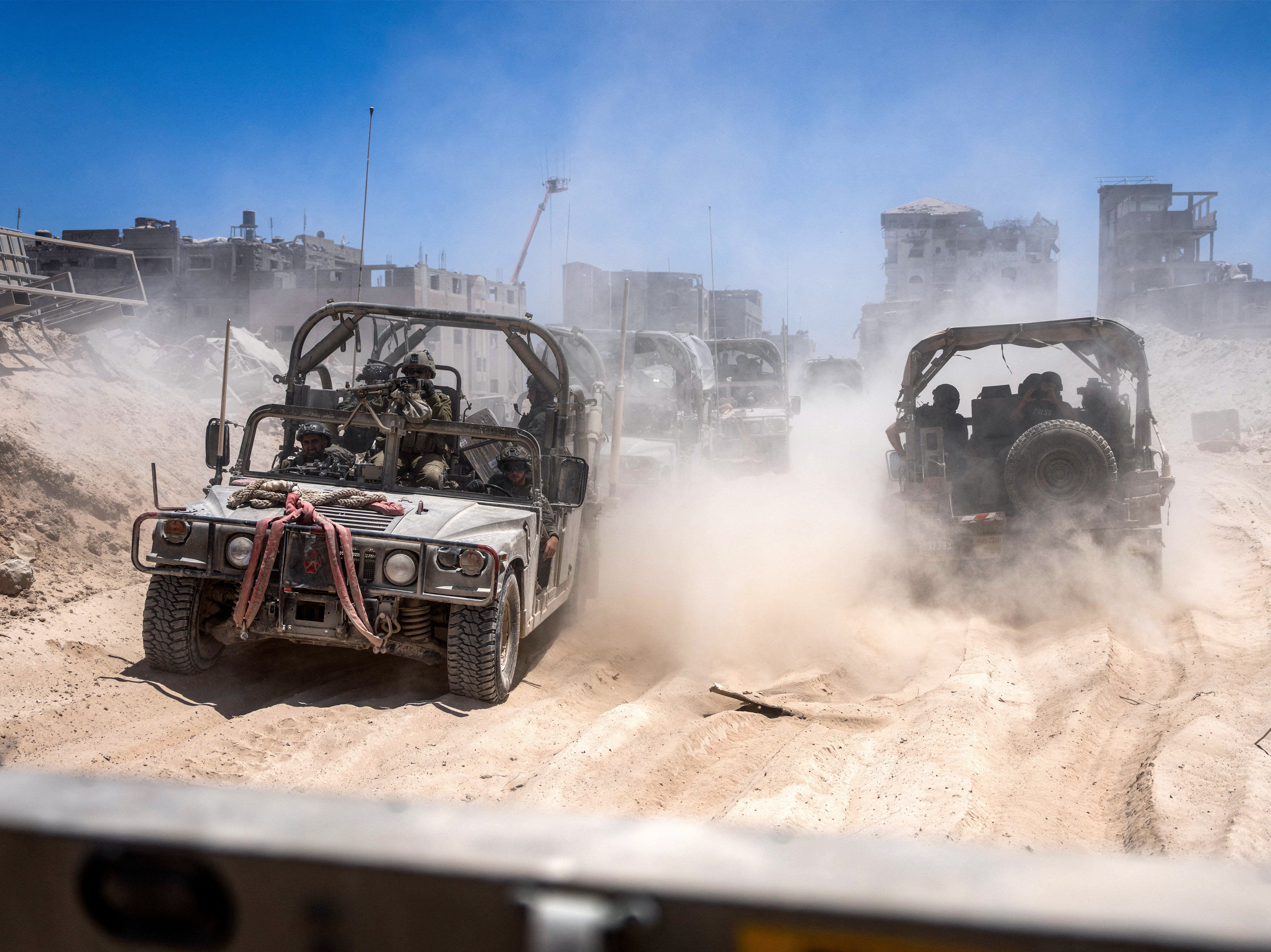 Israeli army vehicles transport a group of soldiers and journalists inside the southern Gaza Strip