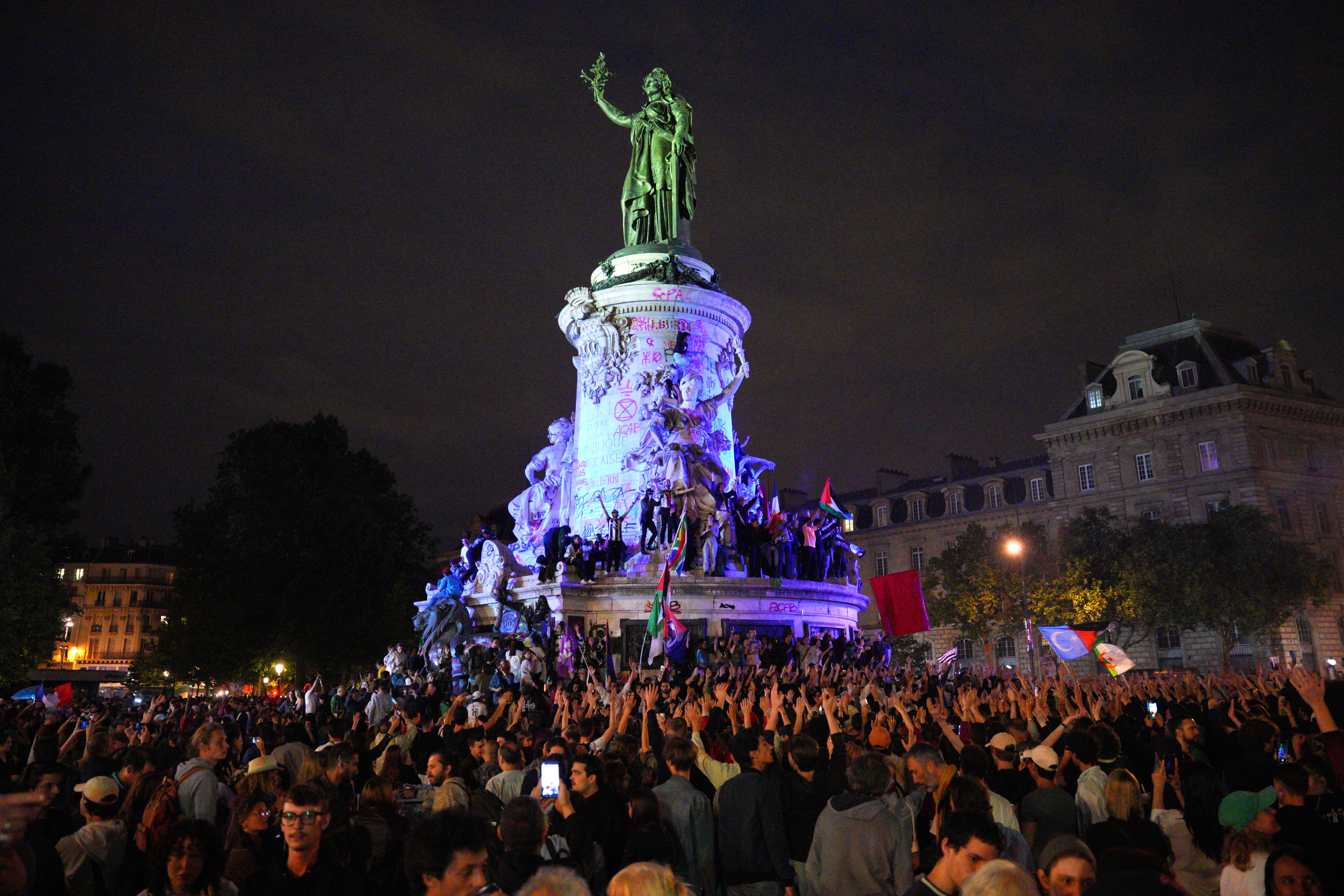 Demonstrators climb on the Monument a la Republique during a protest following the legislative election results in France