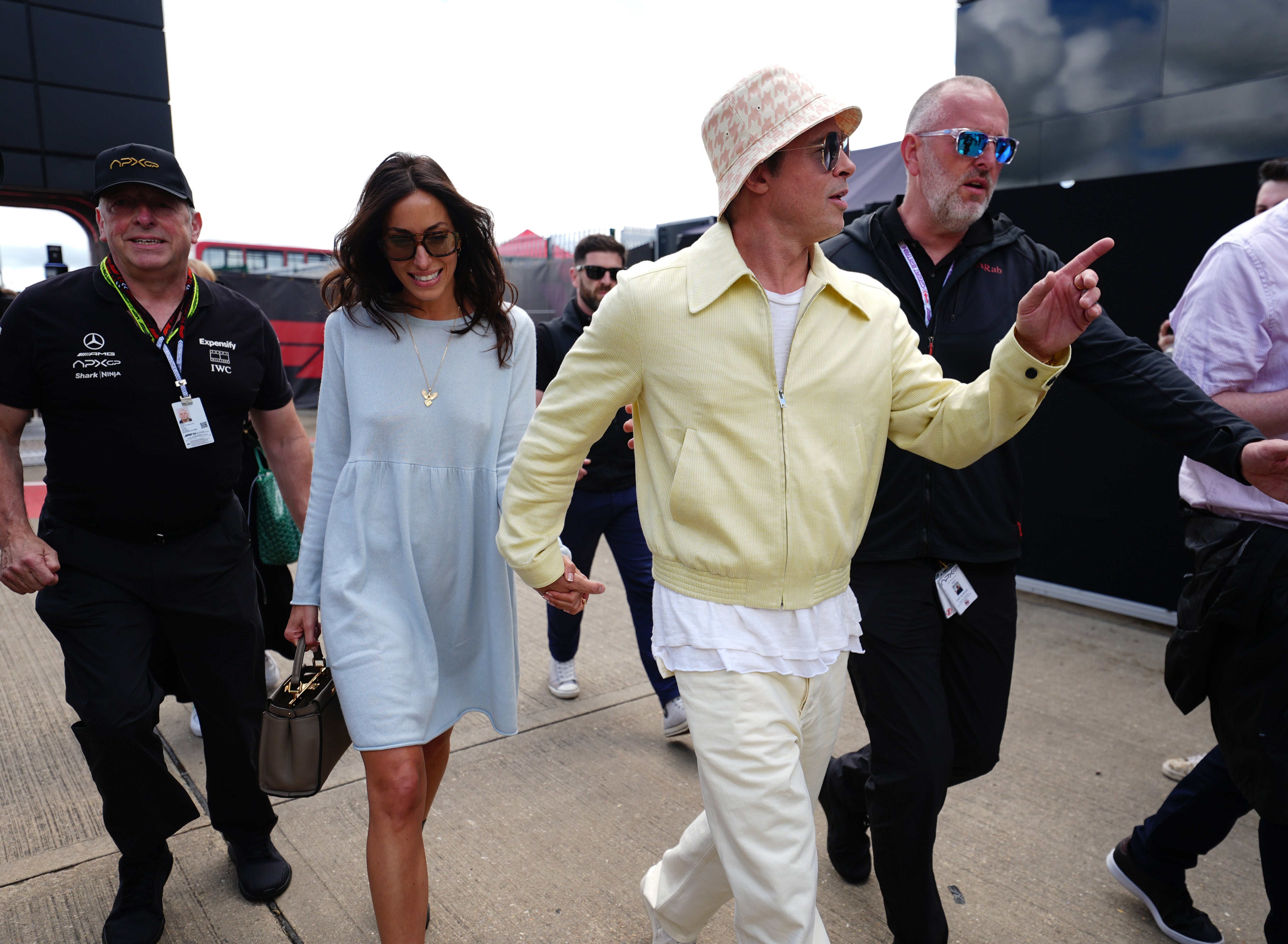 The pair smiled in their sunny ensembles despite the cloudy weather (Brad Pitt and Ines de Ramon arrive in complimenting primary colours at Silverstone (David Davies/PA)