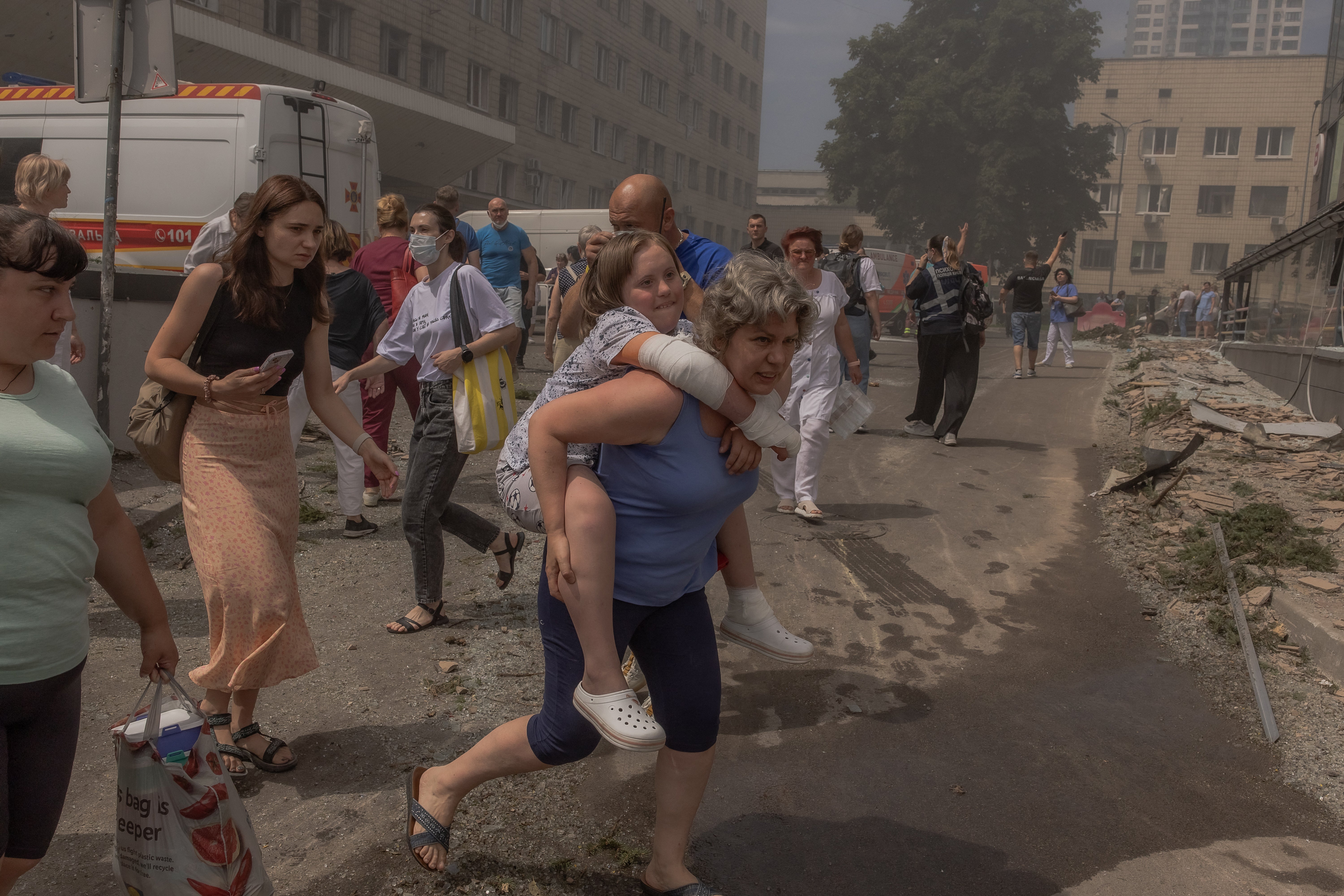 A woman carries a girl from the Okhmatdyt hospital