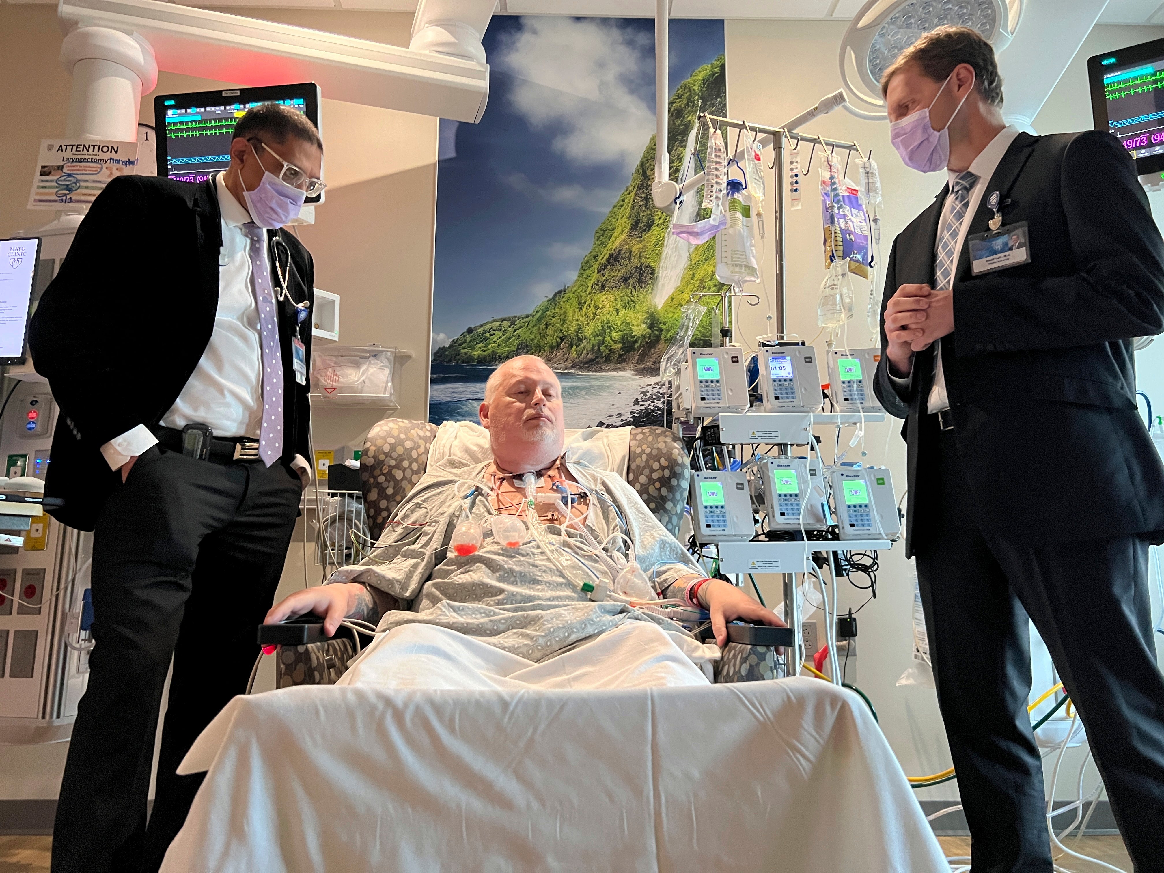 Dr. Girish Mour, left, medical director of Mayo Clinic's Larynx and Trachea Transplant Program, and Dr. David Lott, right, standing on either side of Marty Kedian one week after his transplant surgery in Phoenix, March 8, 2024