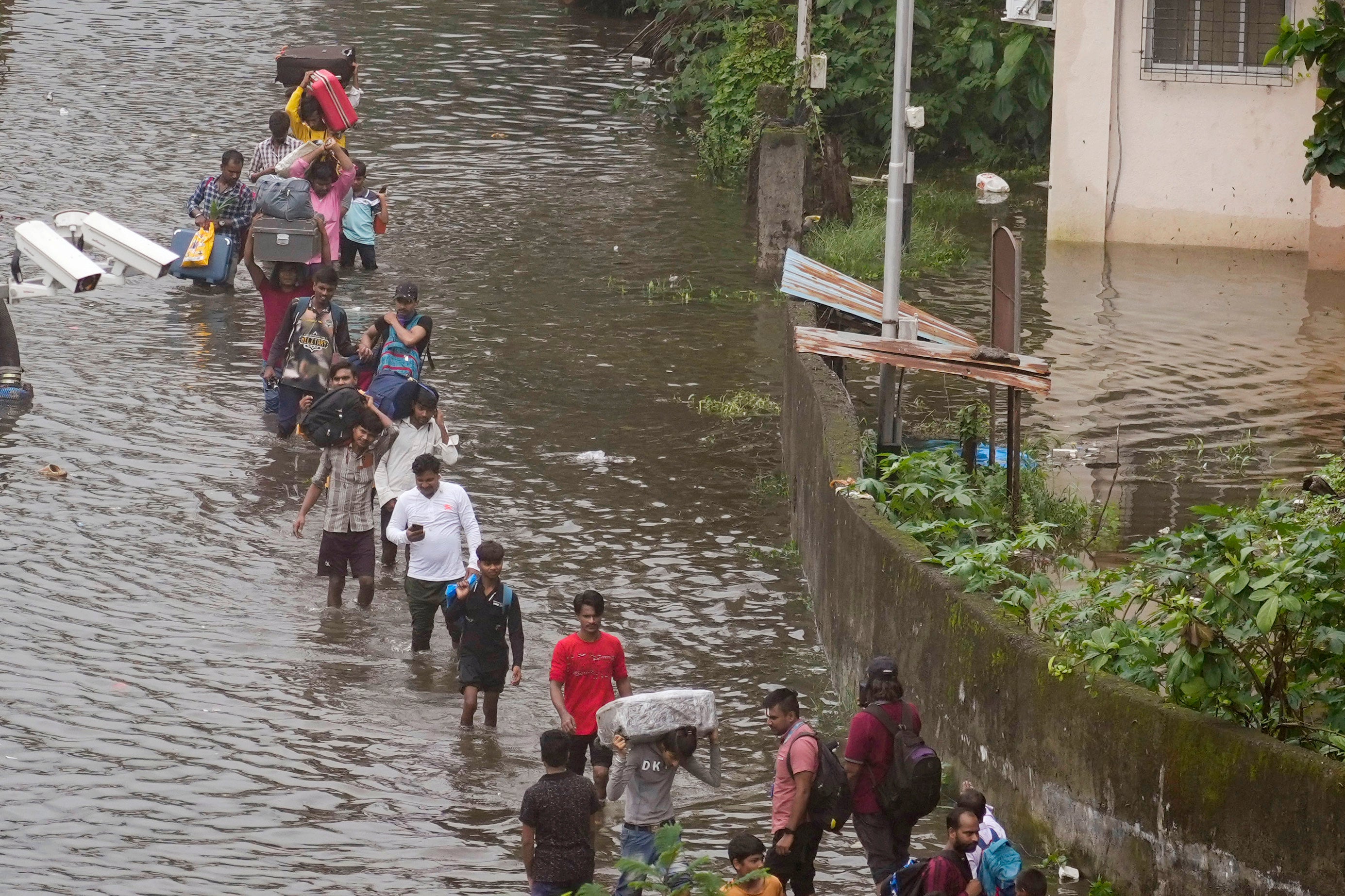 Commuters navigate a submerged street after heavy rainfall in Mumbai on 8 July 2024