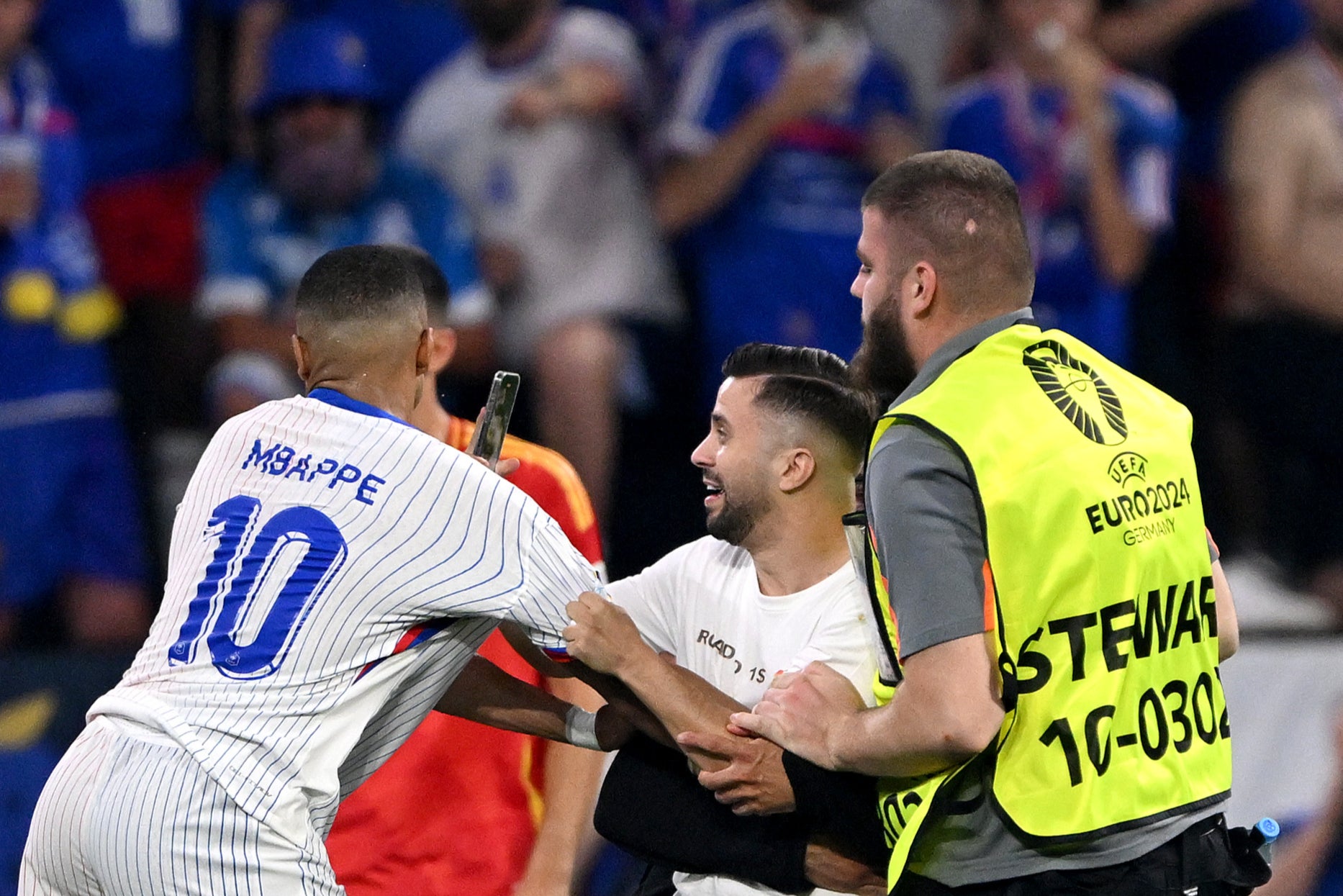 Kylian Mbappe is grabbed by a pitch invader