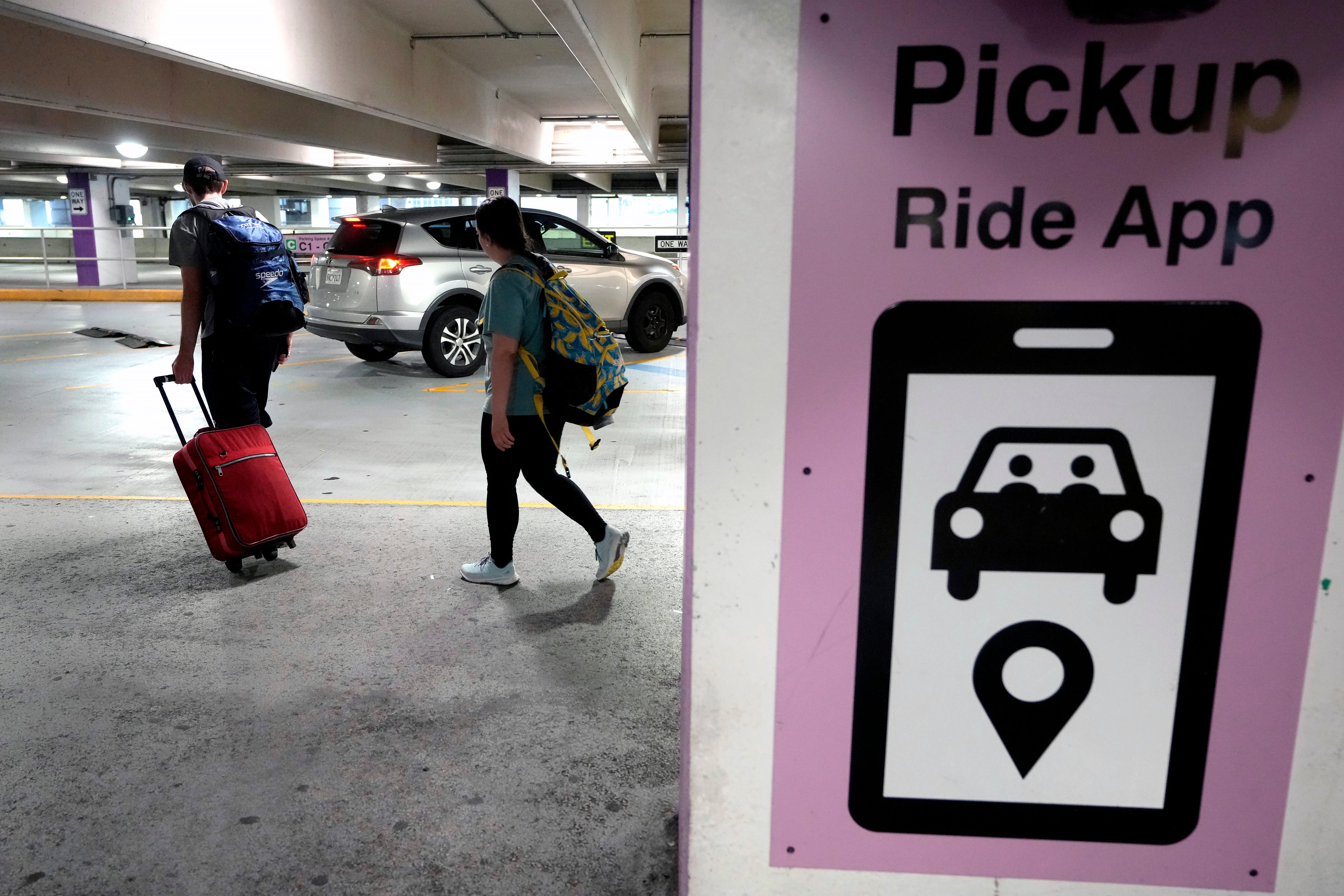 Travelers enter a pick up location for ride-hailing companies, Tuesday, July 9, 2024, in the lower level of a parking garage at Logan International Airport, in Boston