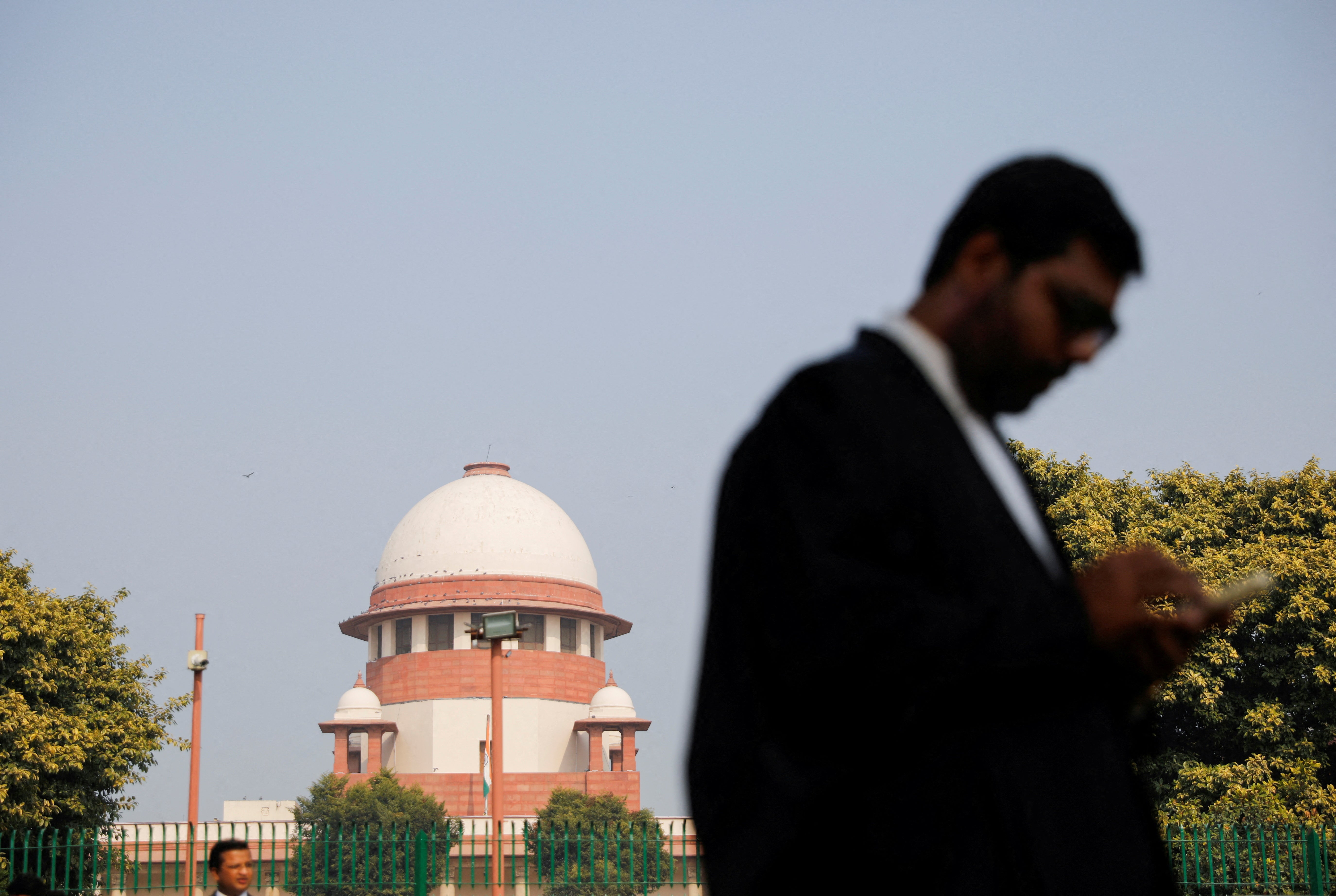 File: A lawyer looks at his mobile phone in front India's supreme court in New Delhi