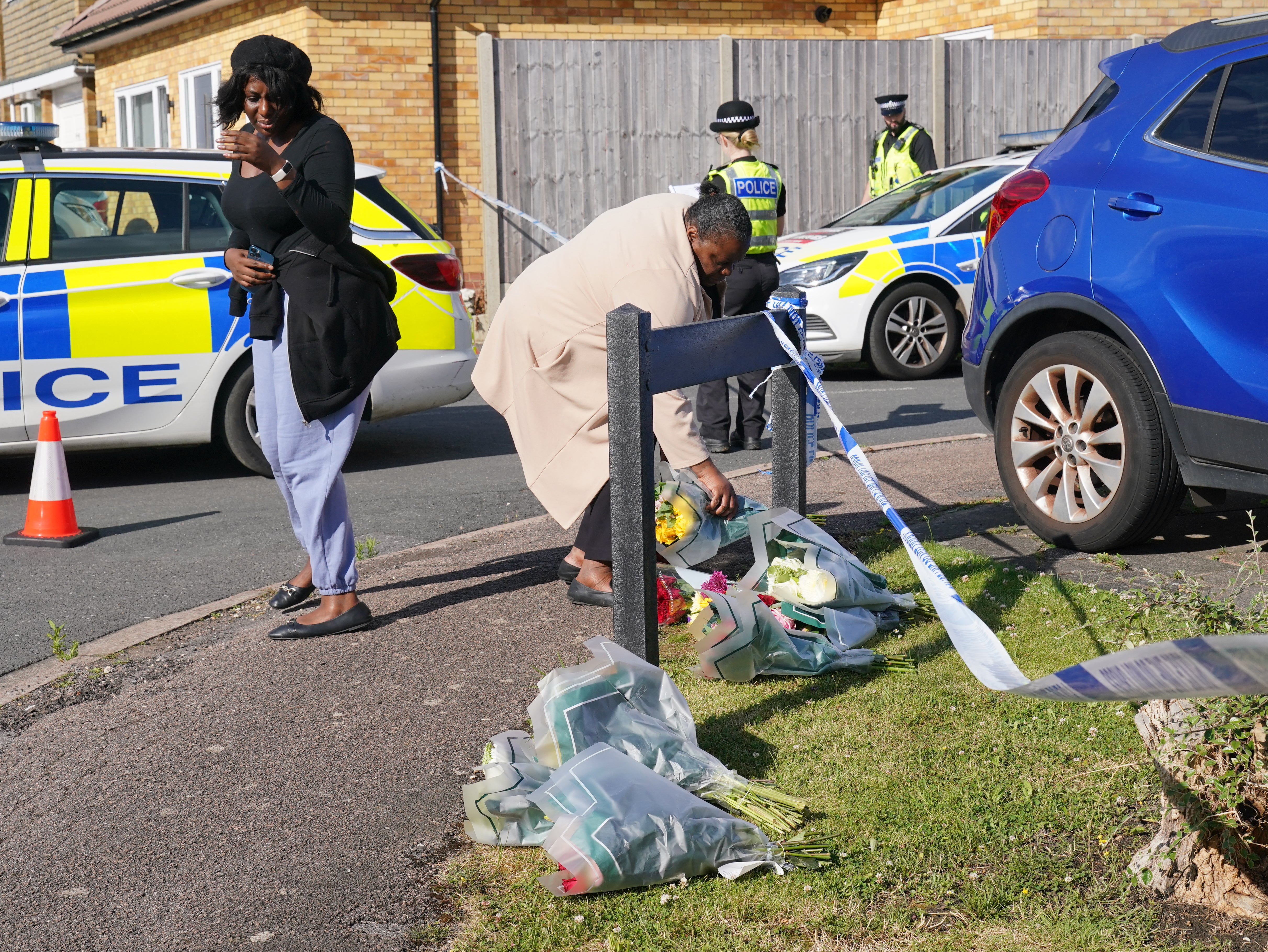 A woman delivers floral tributes near to the scene in Ashlyn Close, Bushey