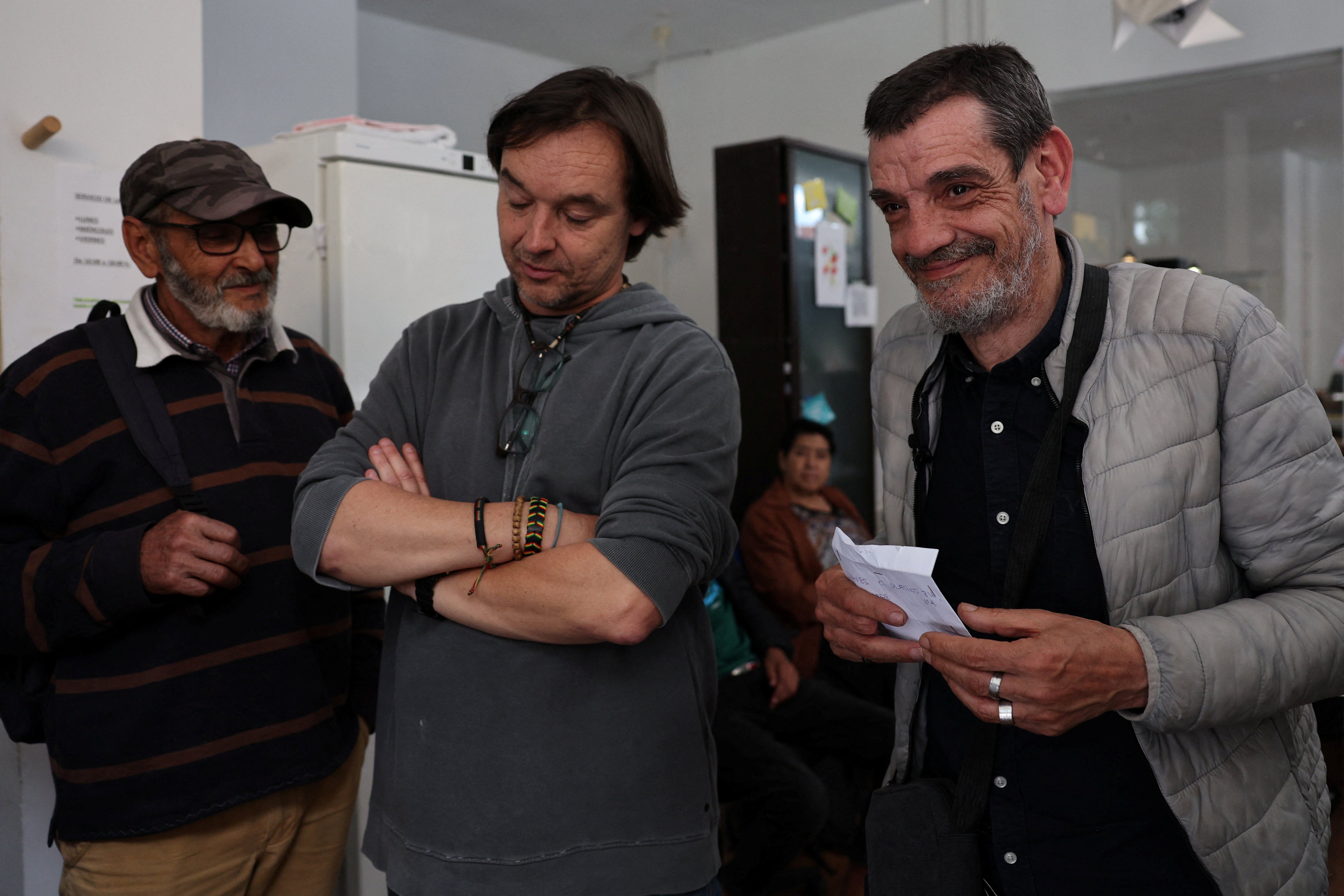 Jose Manuel Guendiano (right) reacts after being handed keys in an envelope by charity Mundo Justo’s (Fair World) head Javier Garcia (center), to an apartment after spending years sleeping rough in Madrid, Spain, May 6, 2024. The apartment belongs to Techo, a social and real estate investment fund that provides rental homes to charity groups working with the homeless in hopes of helping mitigate a housing crisis in Spaiin