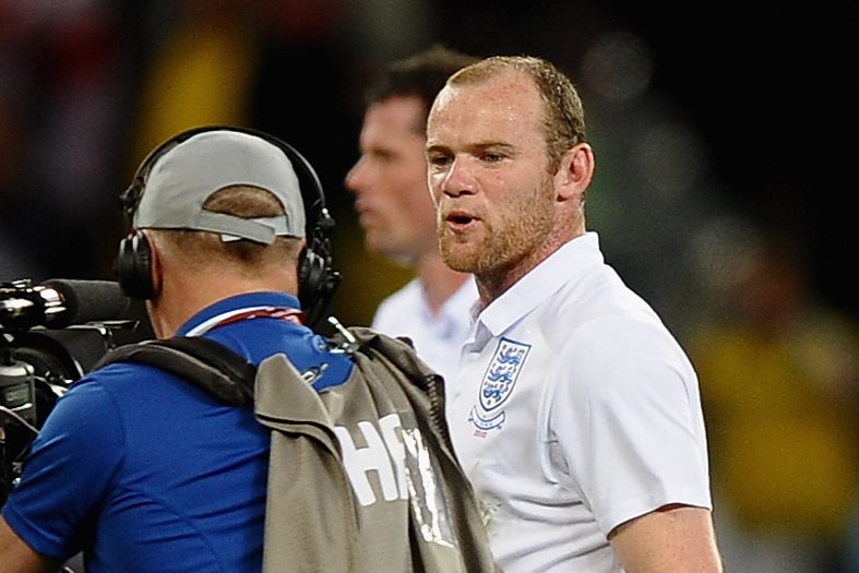 Wayne Rooney of England speaks to a cameraman as he walks off the pitch dejected at the 2010 World Cup