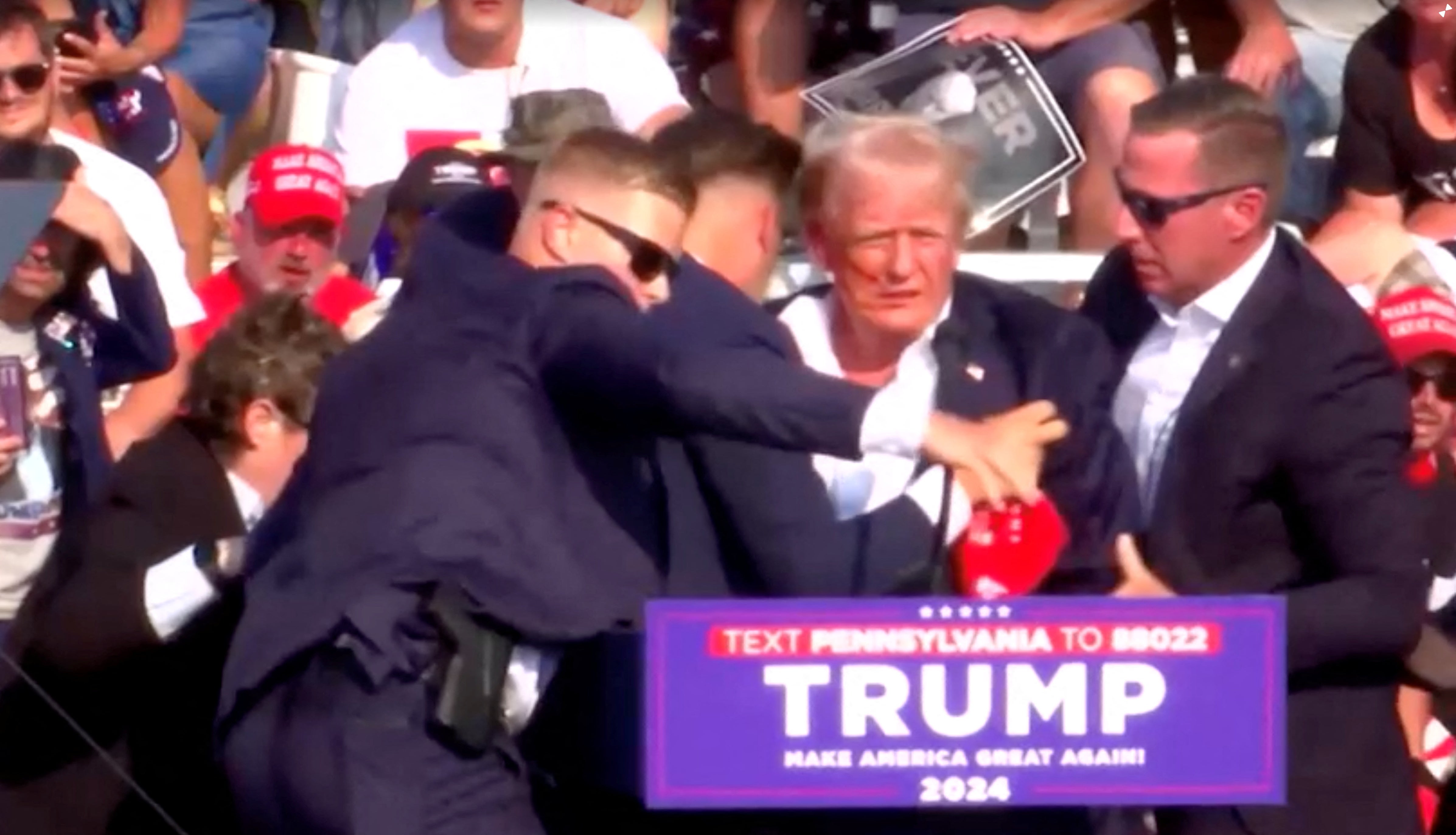 Donald Trump being helped by security personnel after the gunfire