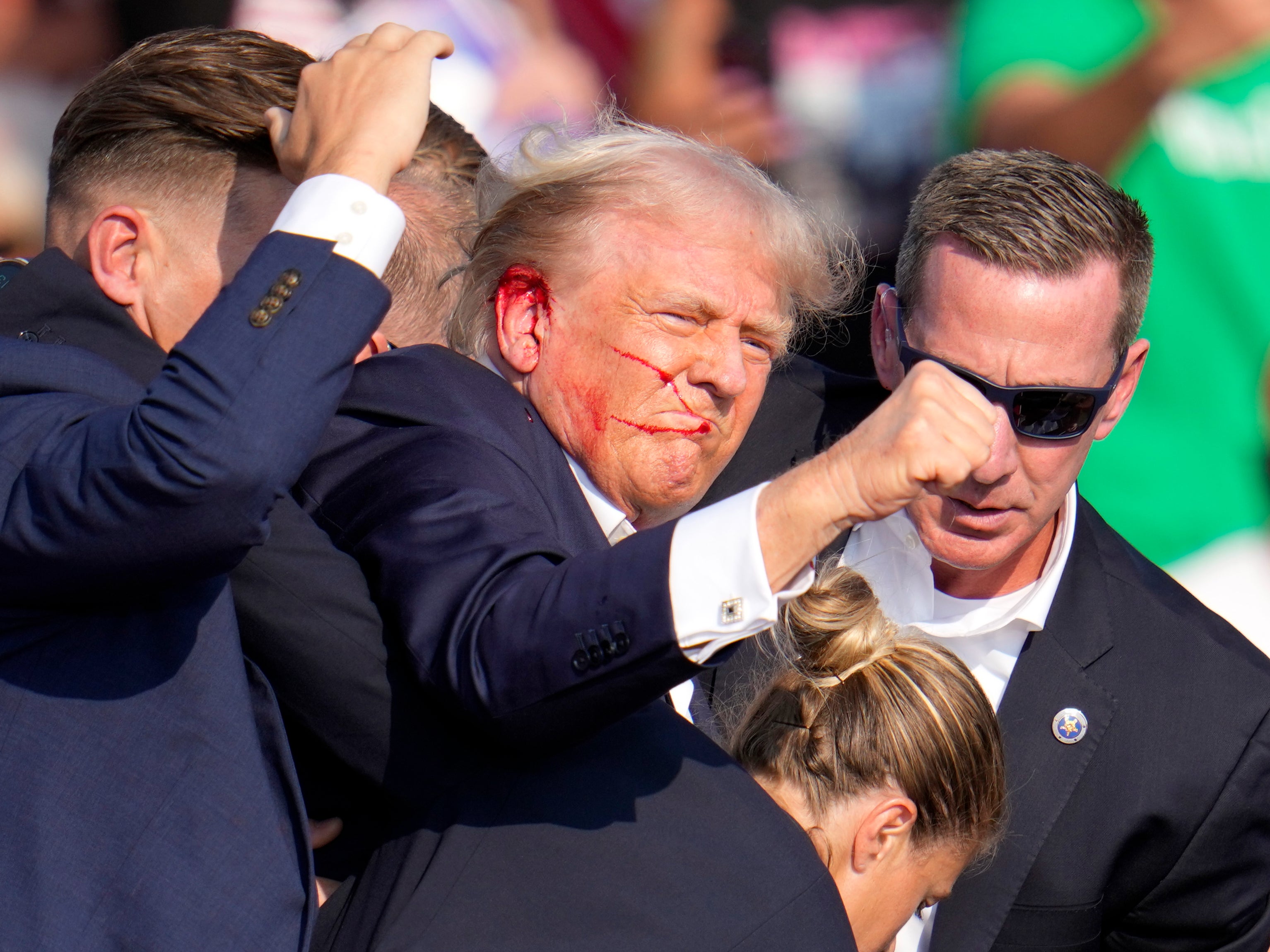 Donald Trump is helped off the stage at a campaign event in Butler, Pennsylvania by Secret Service agents after he is injured in a shooting on Saturday