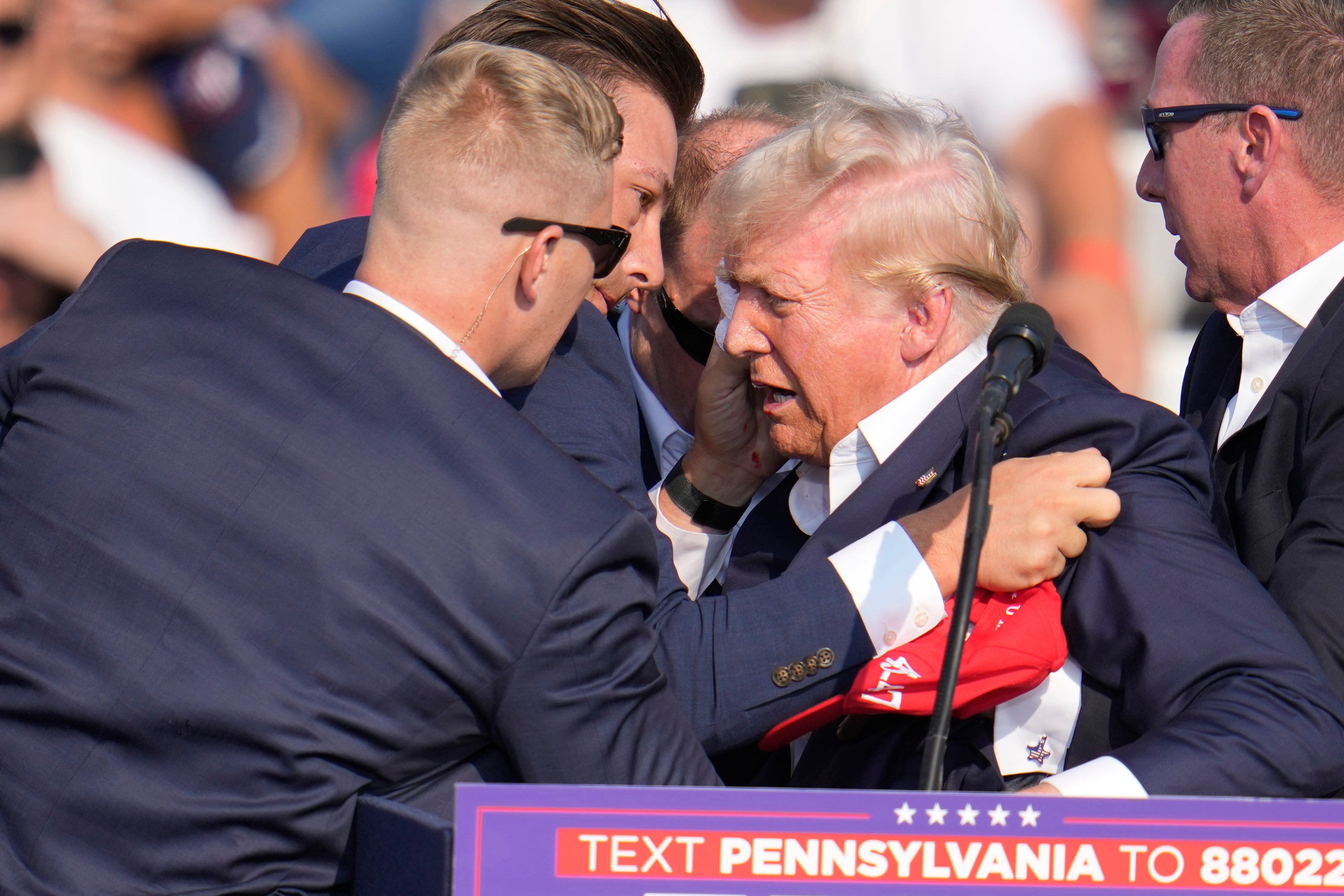 President Trump is helped off stage by US Secret Service agents