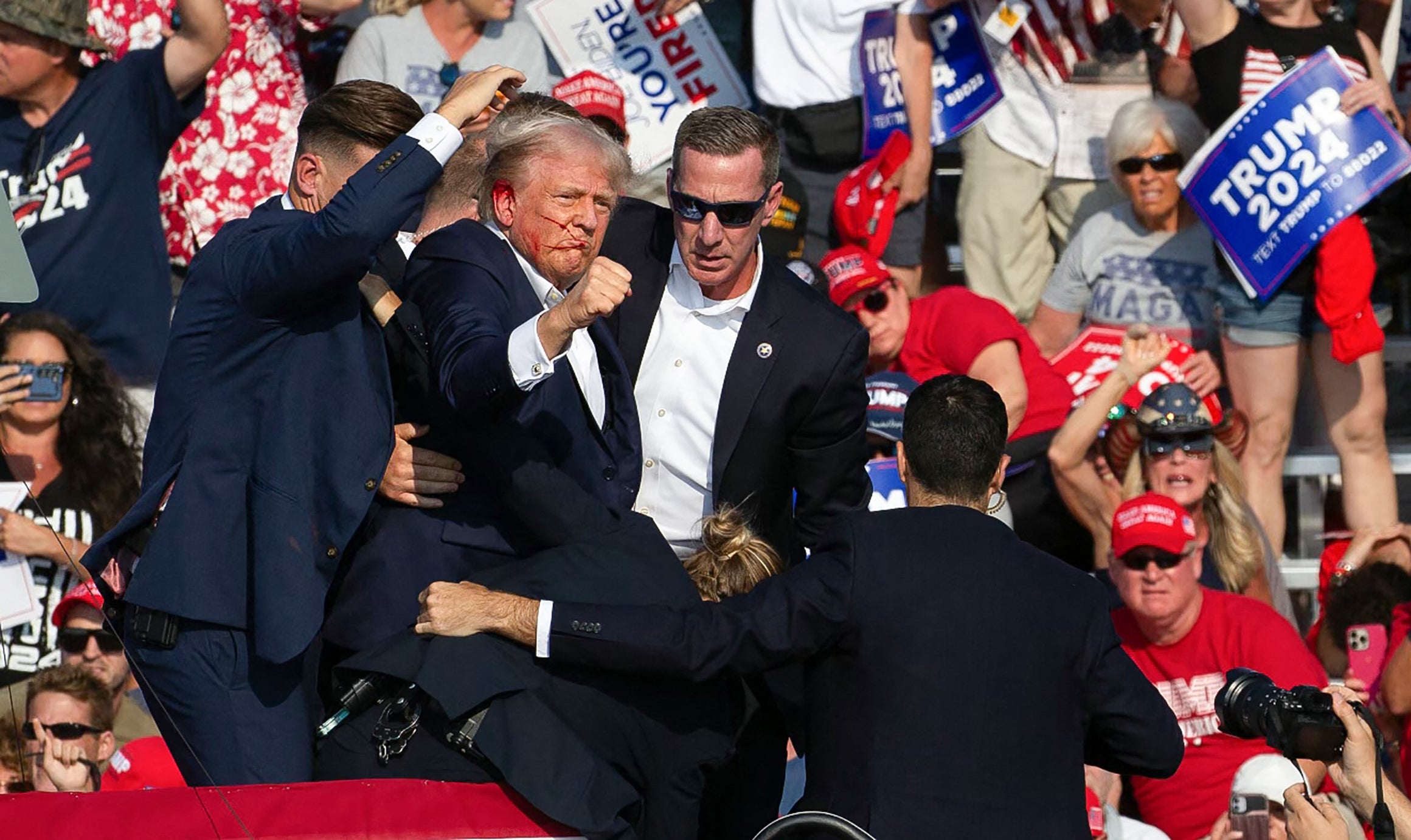 Trump is dragged from the stage, pumping his fist in defiance