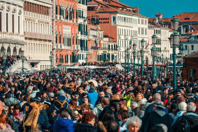 <p>Crowds of tourists walking by typical venetian buildings near San Marco Square during famous  traditional carnival taking place each year in Venice, Italy</p>