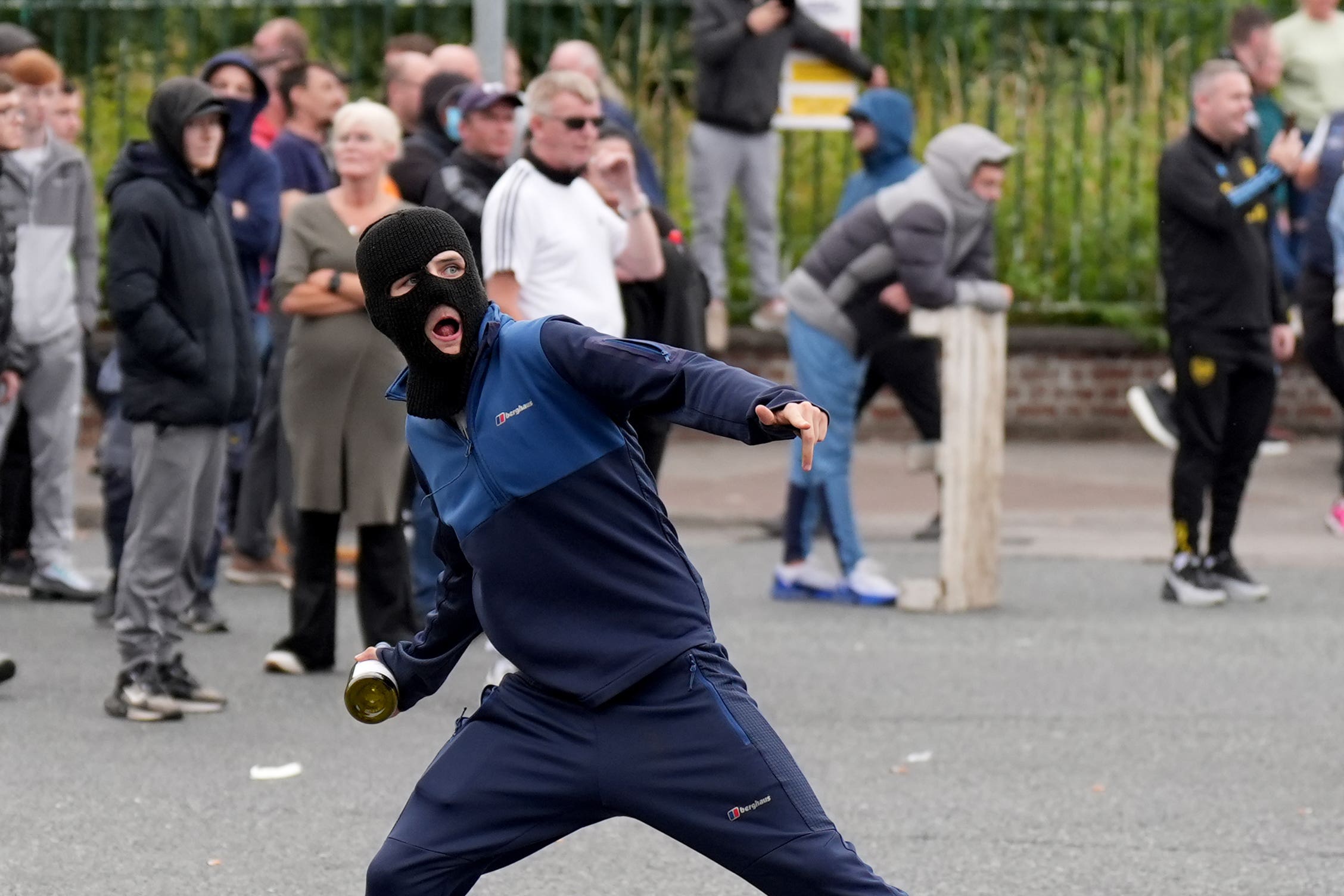 A protester throws a bottle towards gardai officers (Niall Carson/PA)