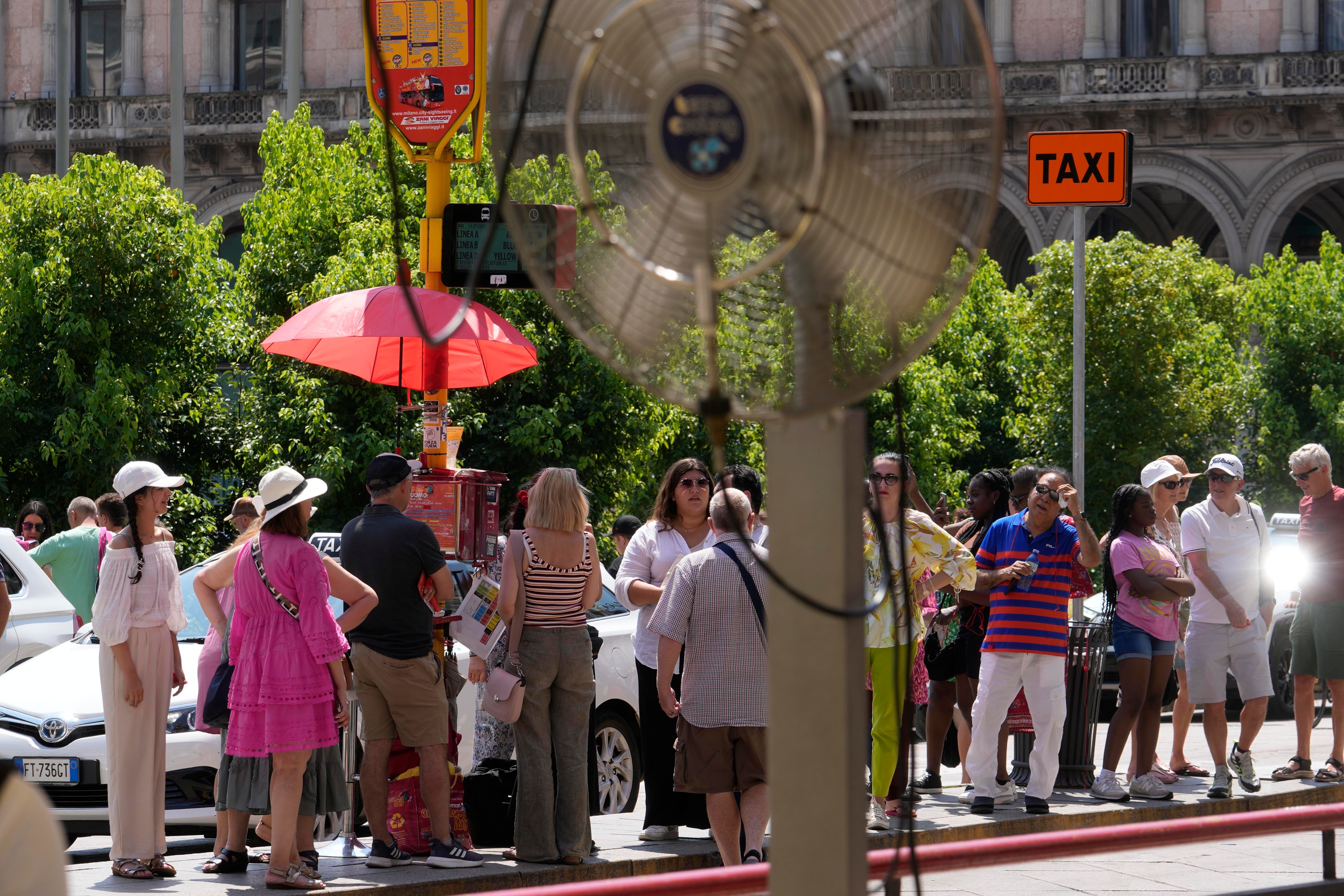 Tourists wait for a bus under the sun in Milan, Italy