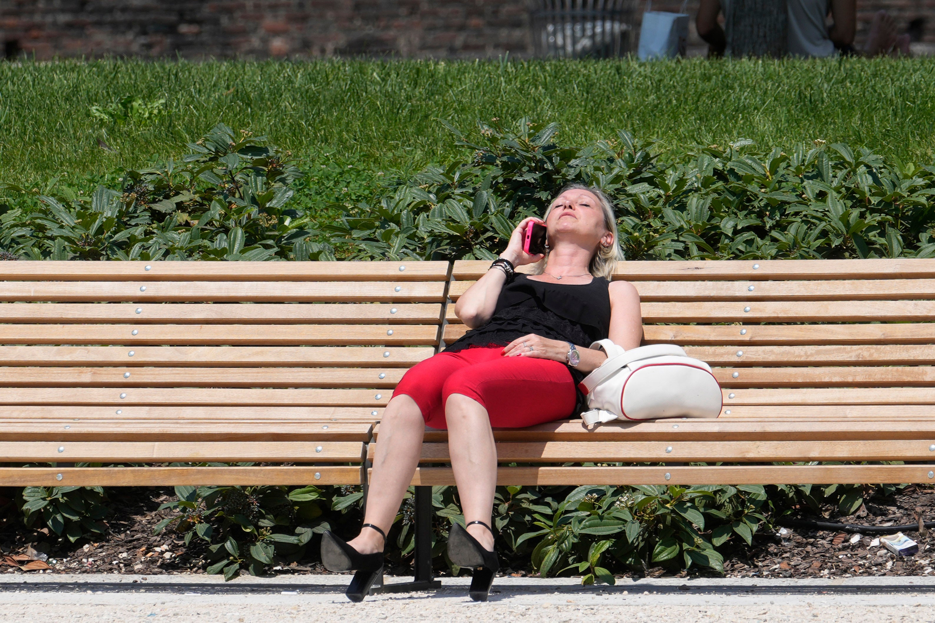 A woman sunbathes in a park in Milan, Italy, Tuesday