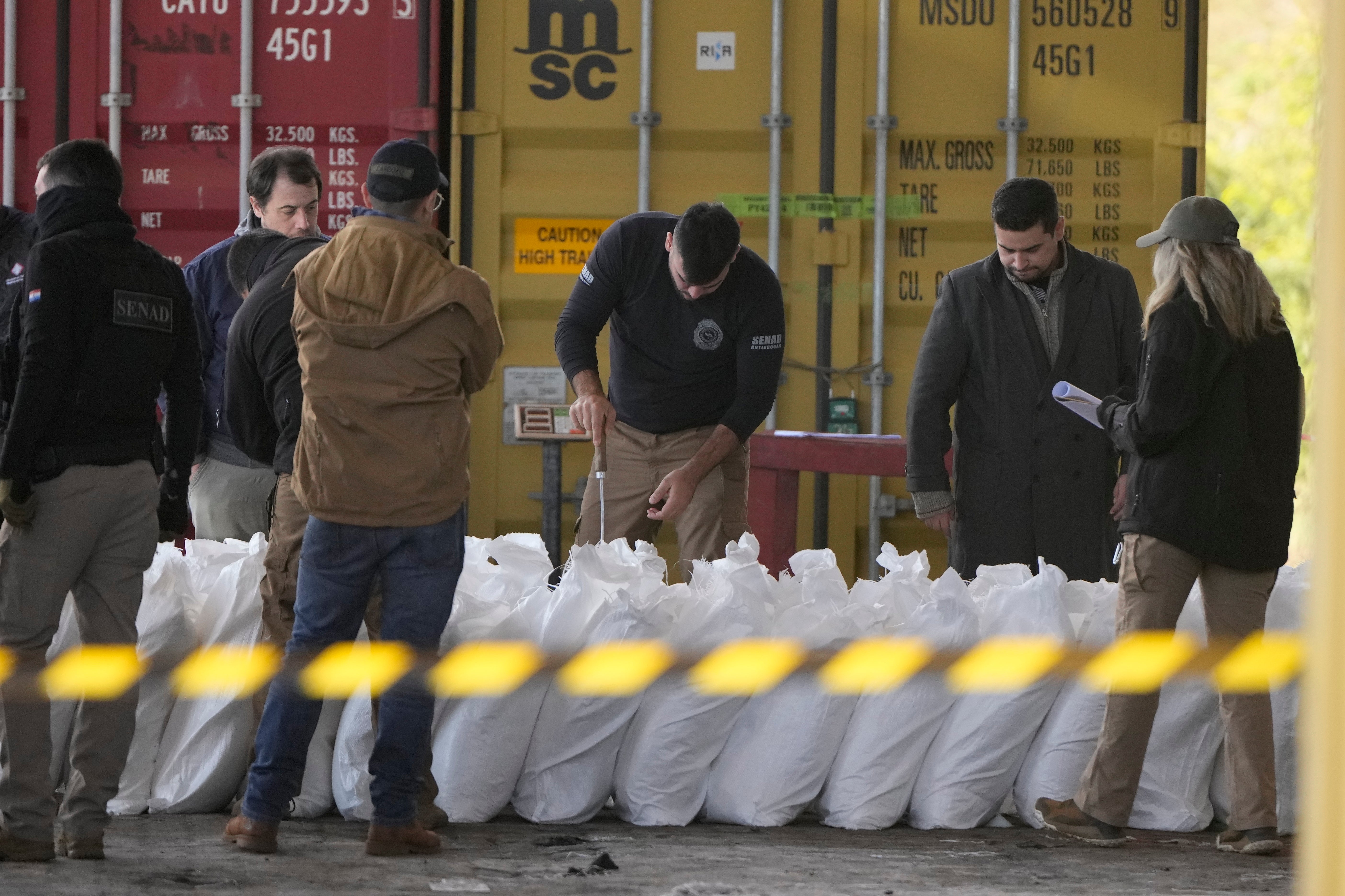 Agents from Paraguay’s anti-drug agency, Senad, inspect sacks of sugar at the port of Caacupemi in Asuncion, Paraguay