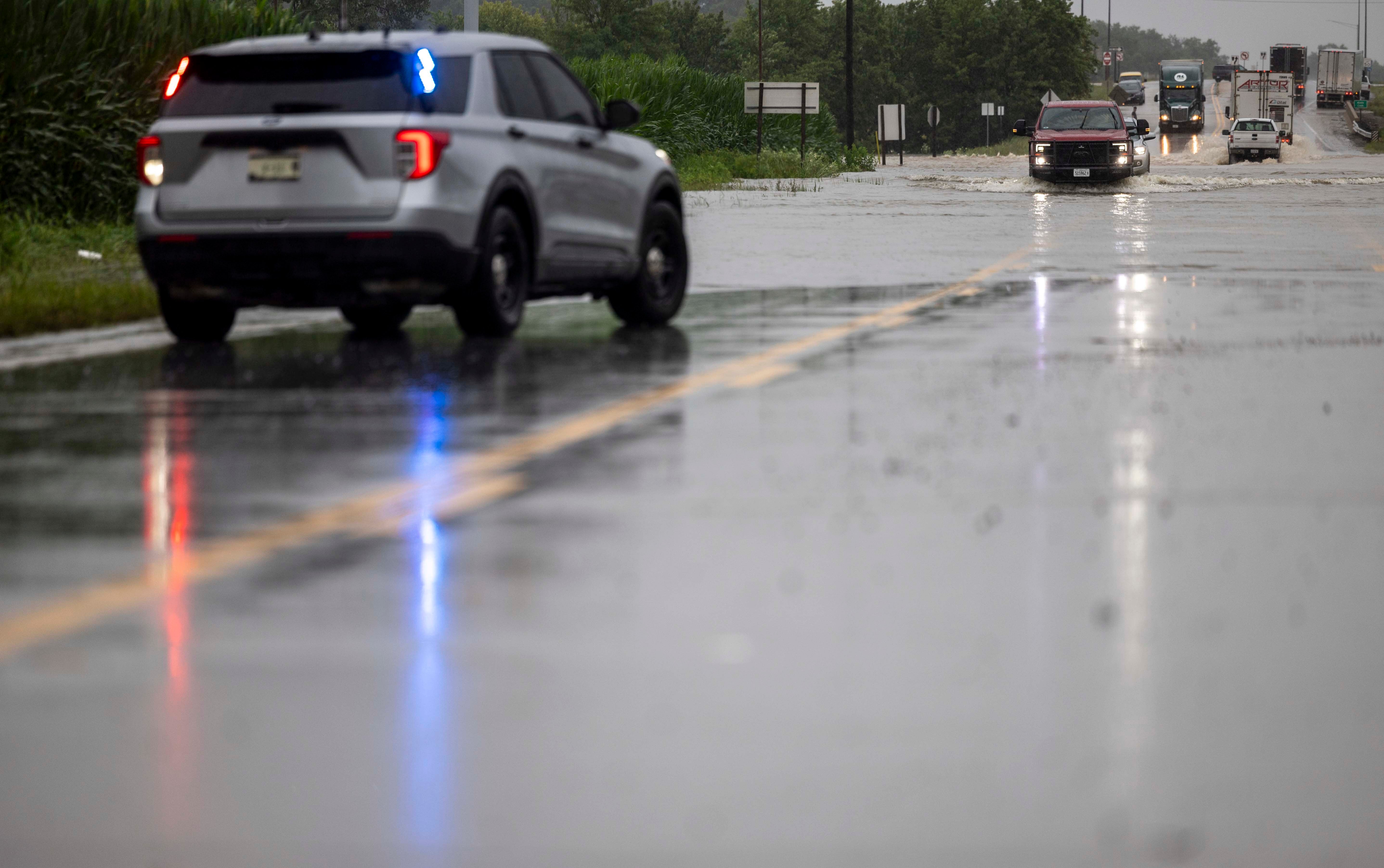 The last set of cars drives through flooding on Illinois State Route 127, south of Interstate 64, before police shut down the road in Nashville, Ill. on Tuesday, July 16, 2024