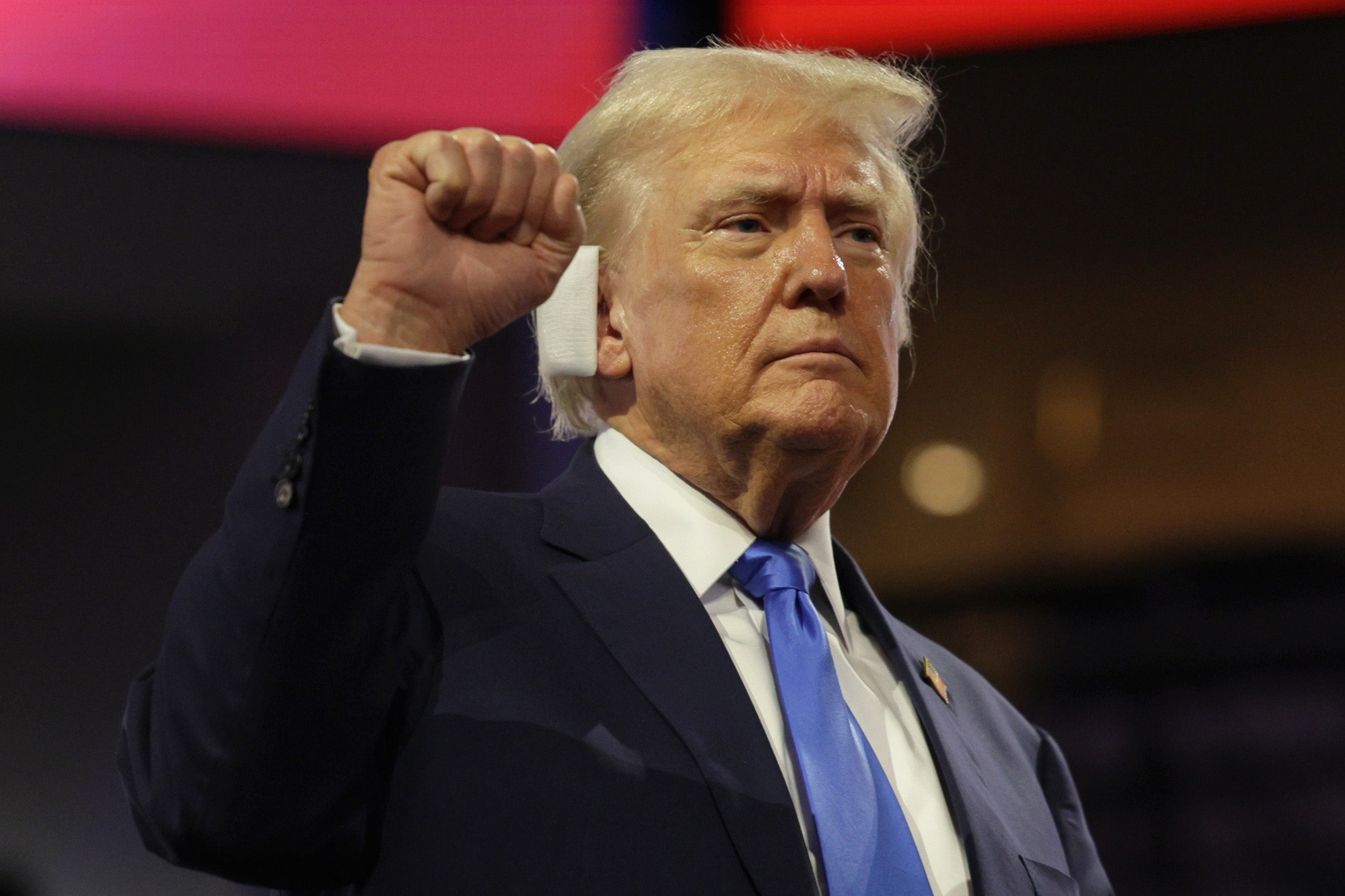 Trump gestures on the second day of the Republican National Convention with a bandage over his wounded ear