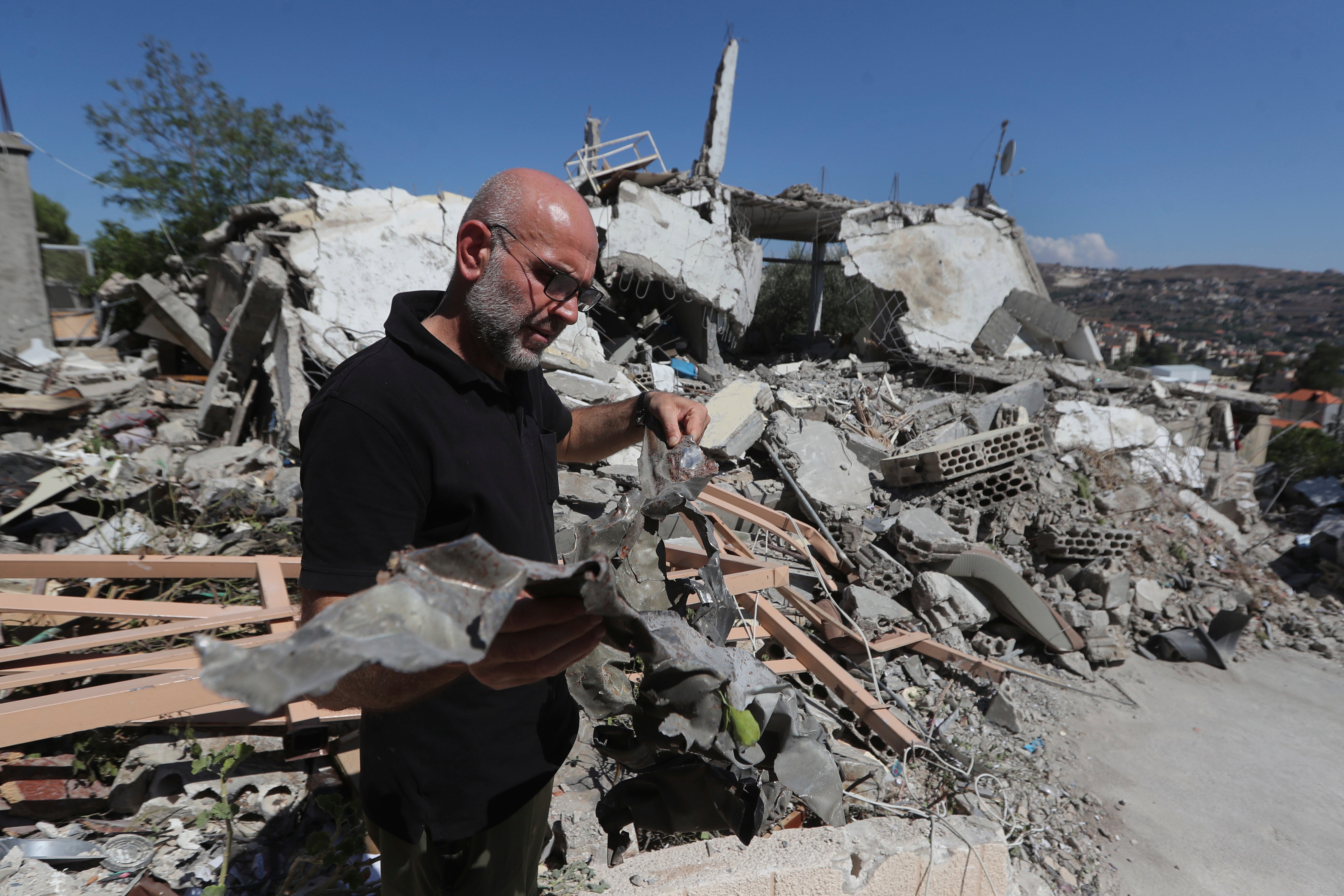 A man shows the remain of an Israeli warplane missile that hit a house and killed a Hezbollah fighter with two of his civilian family members, in Bint Jbeil town, south Lebanon