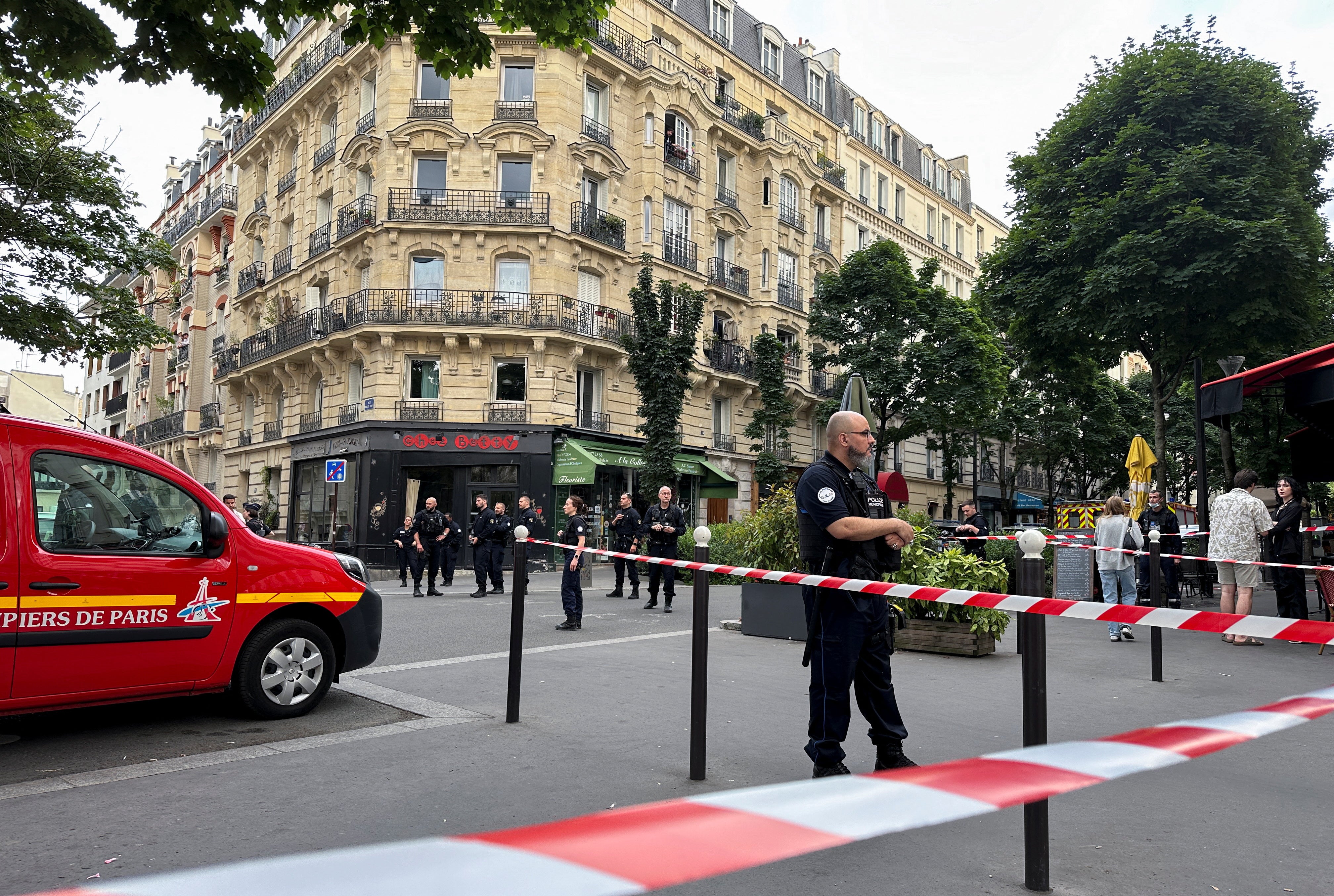 Police officers stand at the scene after a car hit people sitting on a terrace in front of a restaurant in Paris